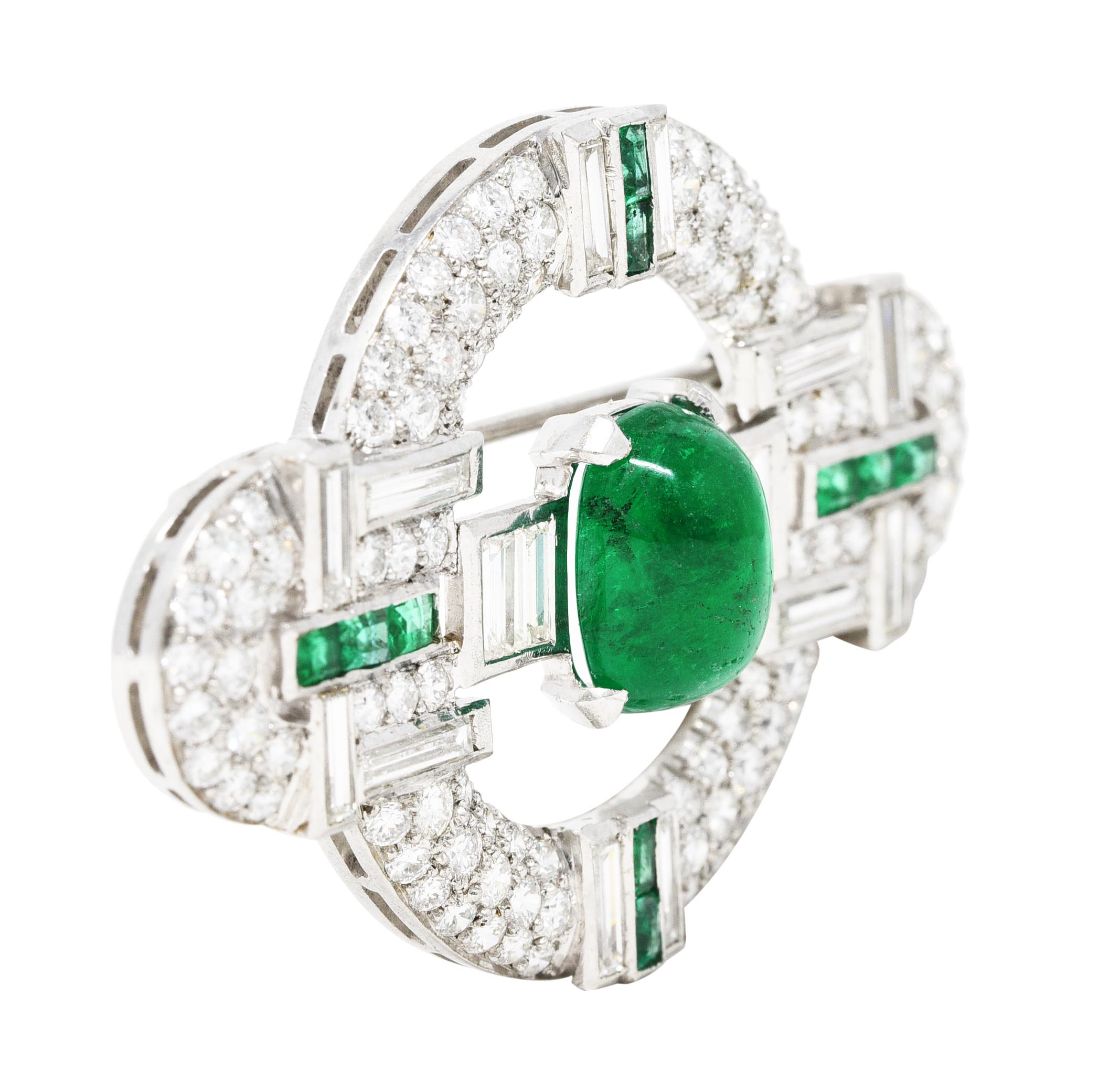 East to West brooch is comprised of a circle motif with arched terminals. Centering a cushion emerald cabochon weighing approximately 4.00 carats. Vibrantly green in color and semi-transparent with natural inclusions. With emerald accents at each