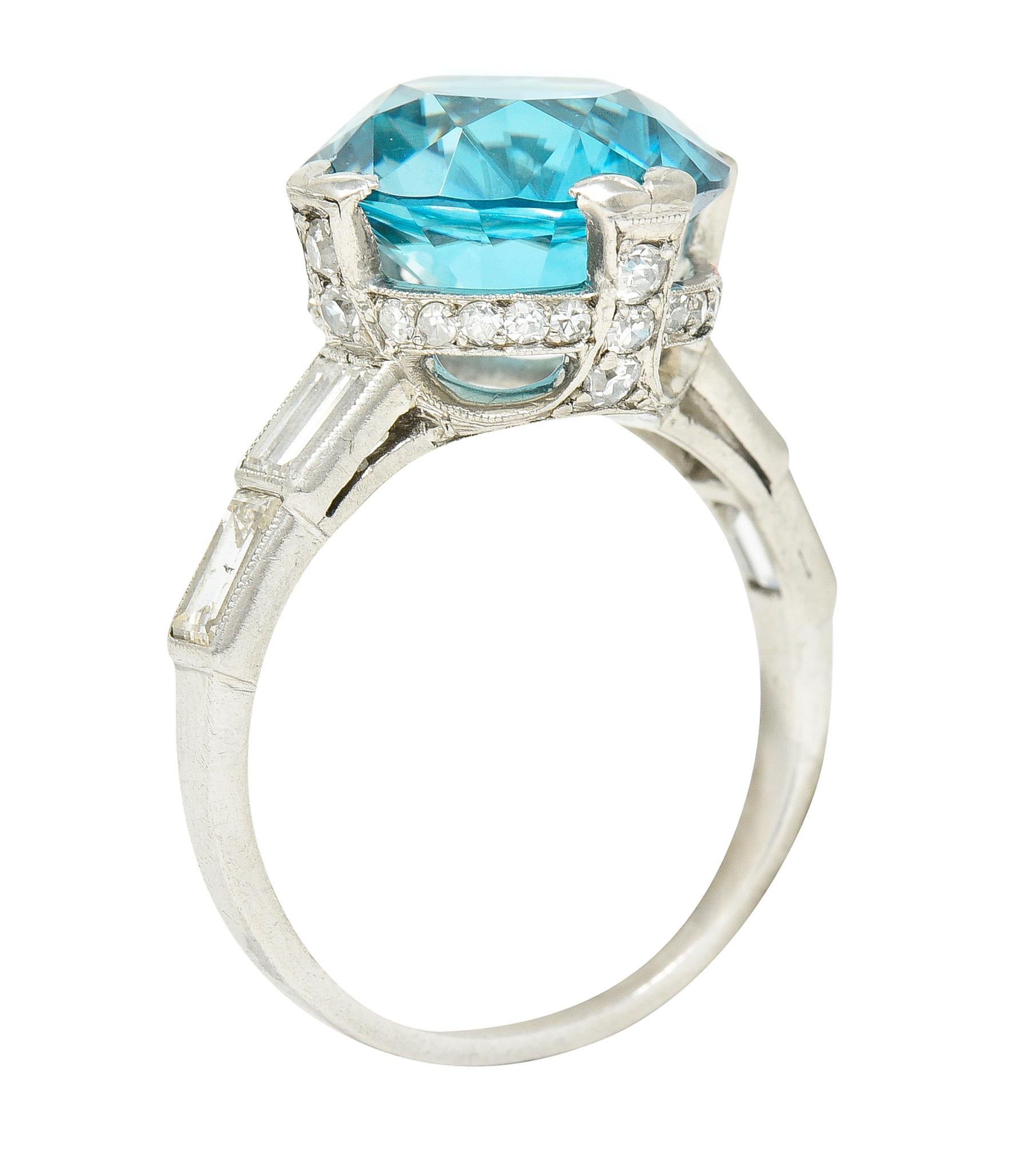 Centering a round cut zircon weighing approximately 8.26 carats - transparent blue in color. Prong set with engraved split prongs in a stylized pierced basket with old single cut diamonds. Bead set and weighing approximately 0.66 carats total - G/H