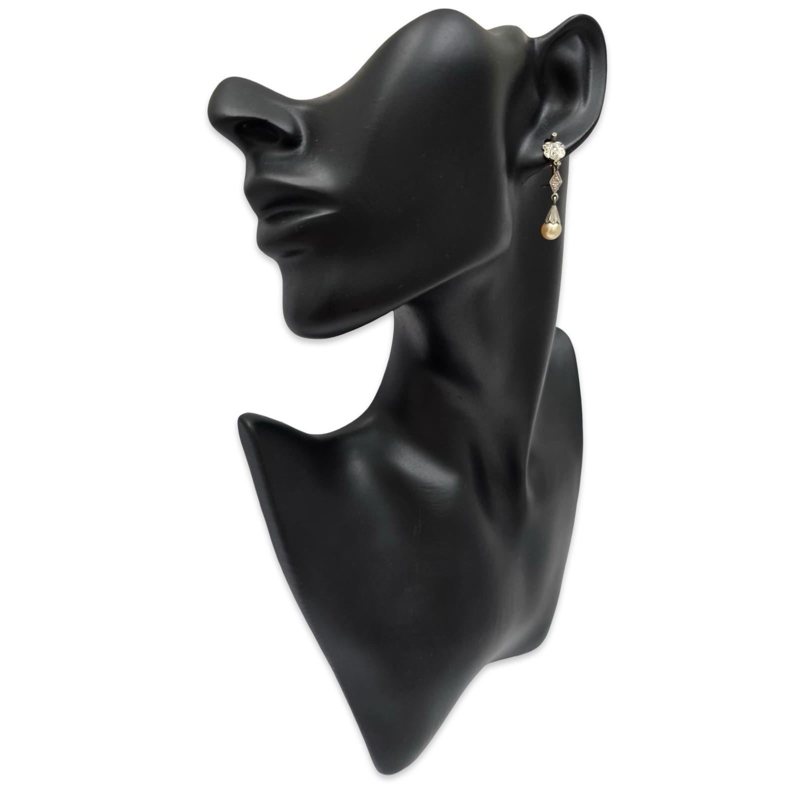 Un raffinato paio di orecchini a goccia in oro Art Deco 9K, che mostrano i motivi geometrici tipici dell'epoca e i dettagli incisi a mano. Ogni orecchino è caratterizzato da una luminosa perla naturale di 6,5 mm sospesa da un pannello intricatamente