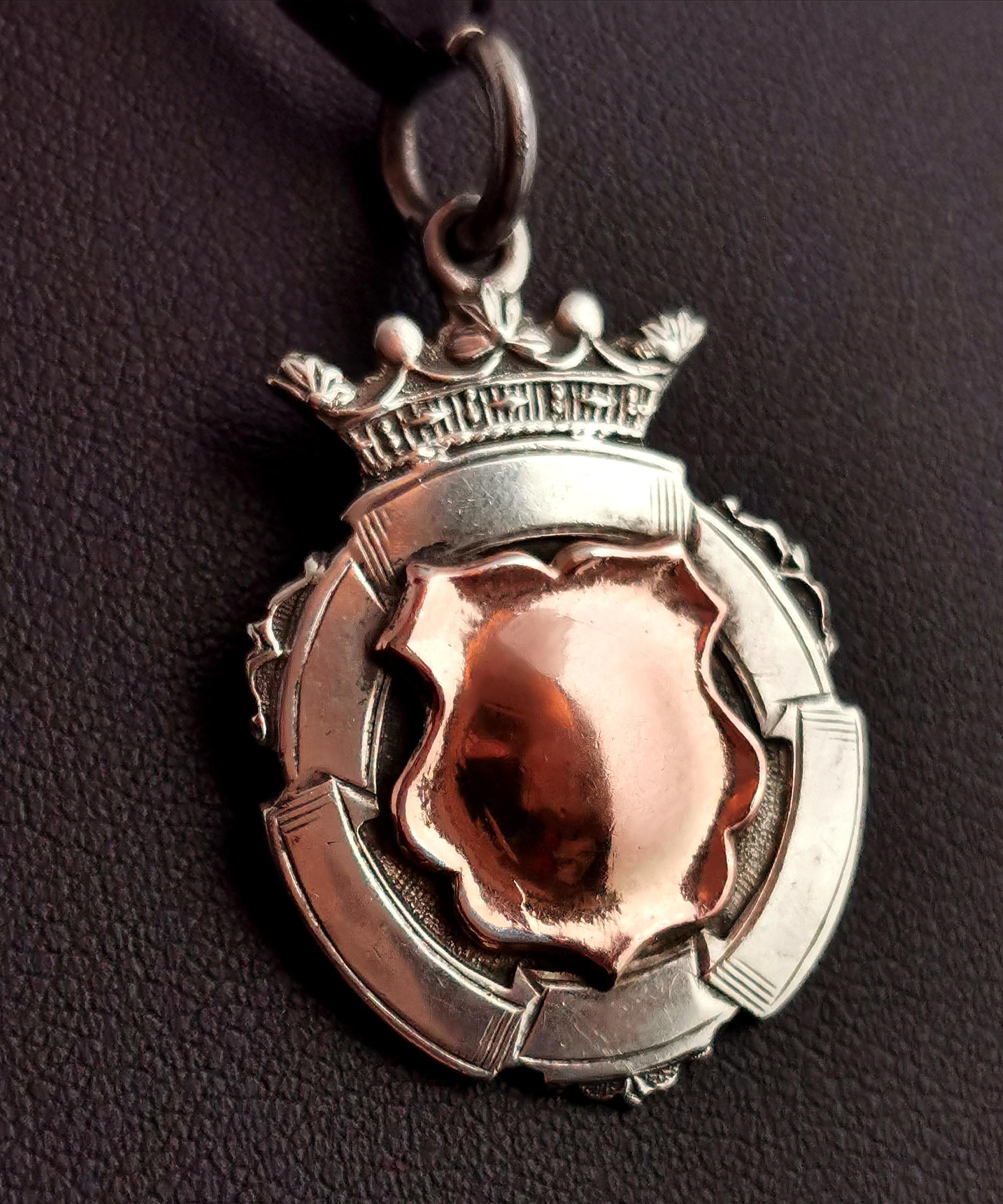 An attractive vintage, early 1930's sterling silver and Rose gold shield fob.

A nice heavy little fob with a decorative design and a 9kt Rose gold cartouche to the centre, this has not been monogrammed or engraved so could be personalised if