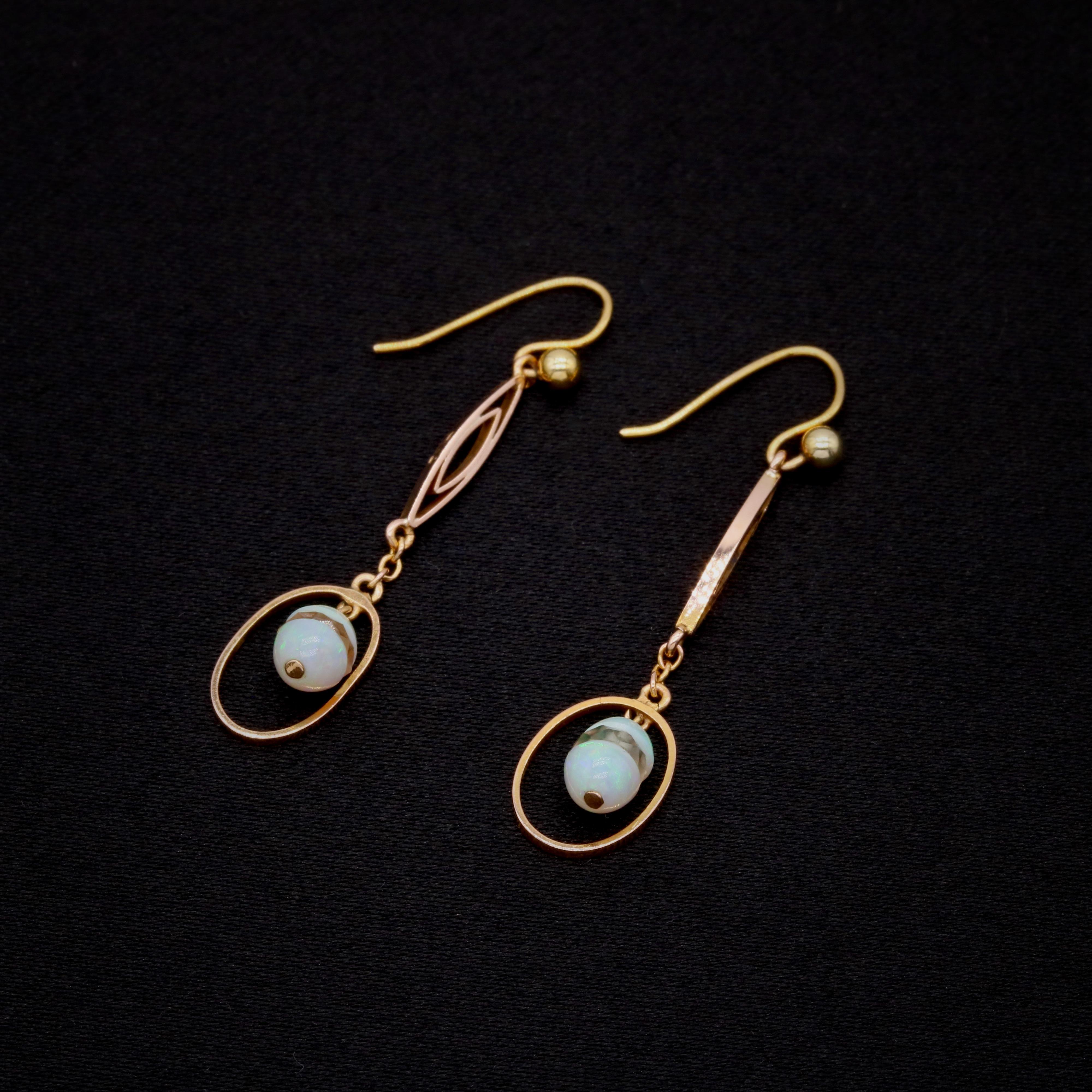 A pair of opal, rock crystal, and yellow gold earrings, each comprising two opal cabochons, a panel of faceted rock crystal, in 9 karat yellow gold. 

These dainty, unusual earrings are formed as a cabochon opal ‘egg’ shape, split into 2 and