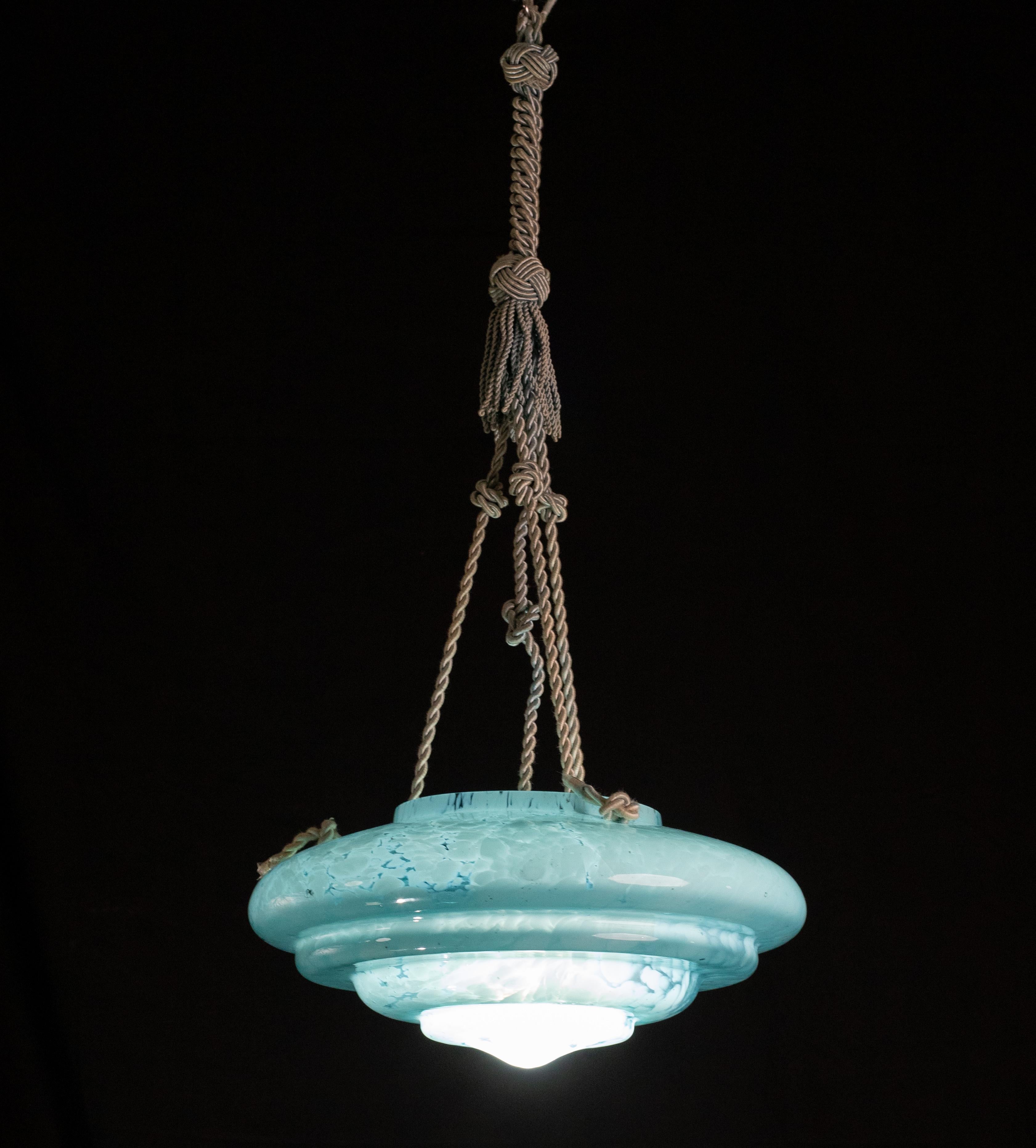 Superbe pendentif en verre de Murano de couleur aqua marina.

Style Art déco : période de fabrication 1940-1950.

Le disque du lustre est de couleur aigue-marine avec des reflets blancs suspendus aux trois cordes d'origine.

Une lampe e27.

Diamètre