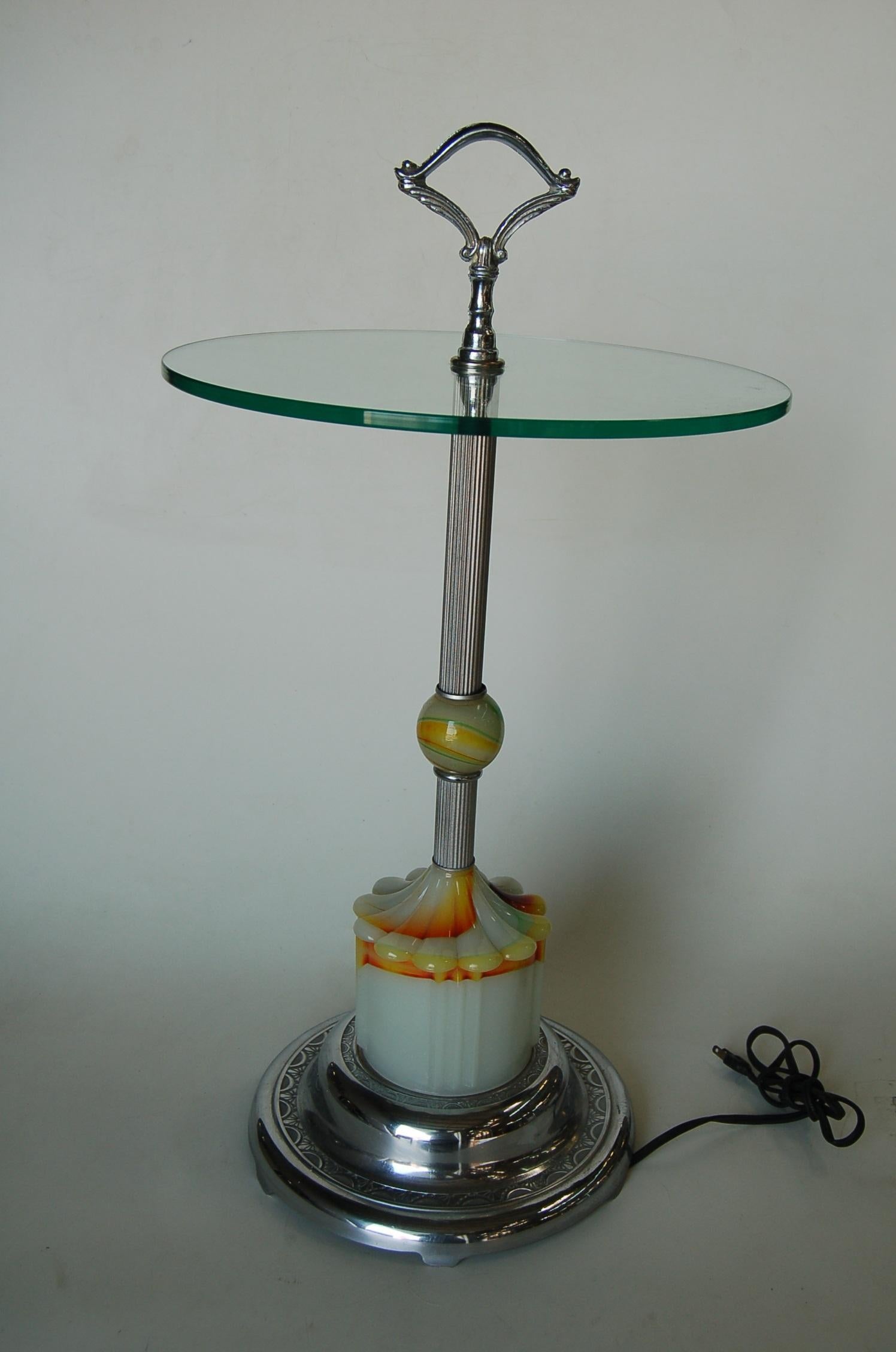 This 1930s Art Deco side accent table or end table made of agate glass, the bottom of which lights up, and a in chrome finial in that crowns the clear glass top. The table rests on a flower-shaped agate Illuminating base; the on /off switch is
