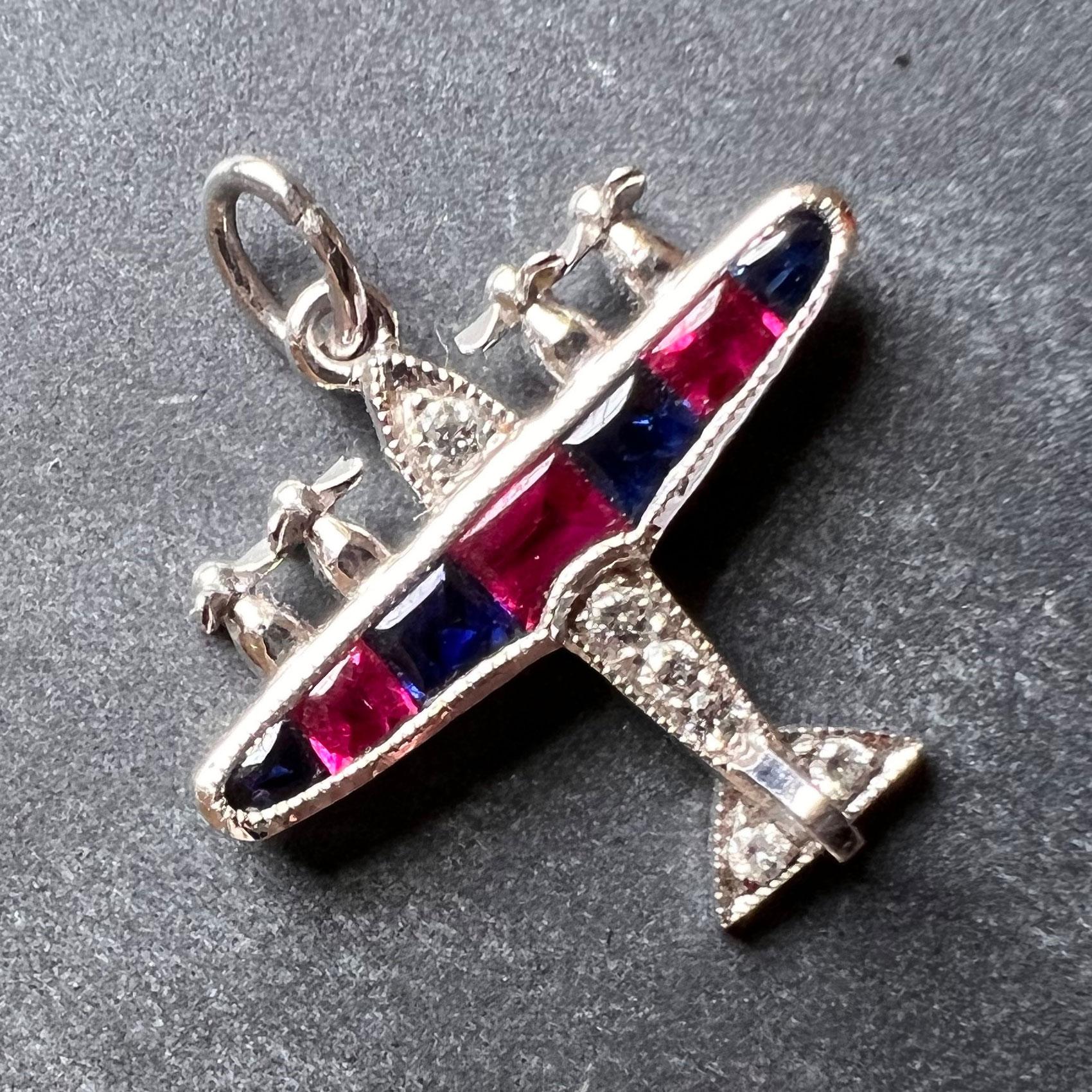 An Art Deco platinum charm pendant designed as an airplane with ruby and sapphire wings and diamond set body. The charm is set with six round brilliant cut diamonds, three buff-top rubies and four buff-top sapphires. Unmarked but tested for