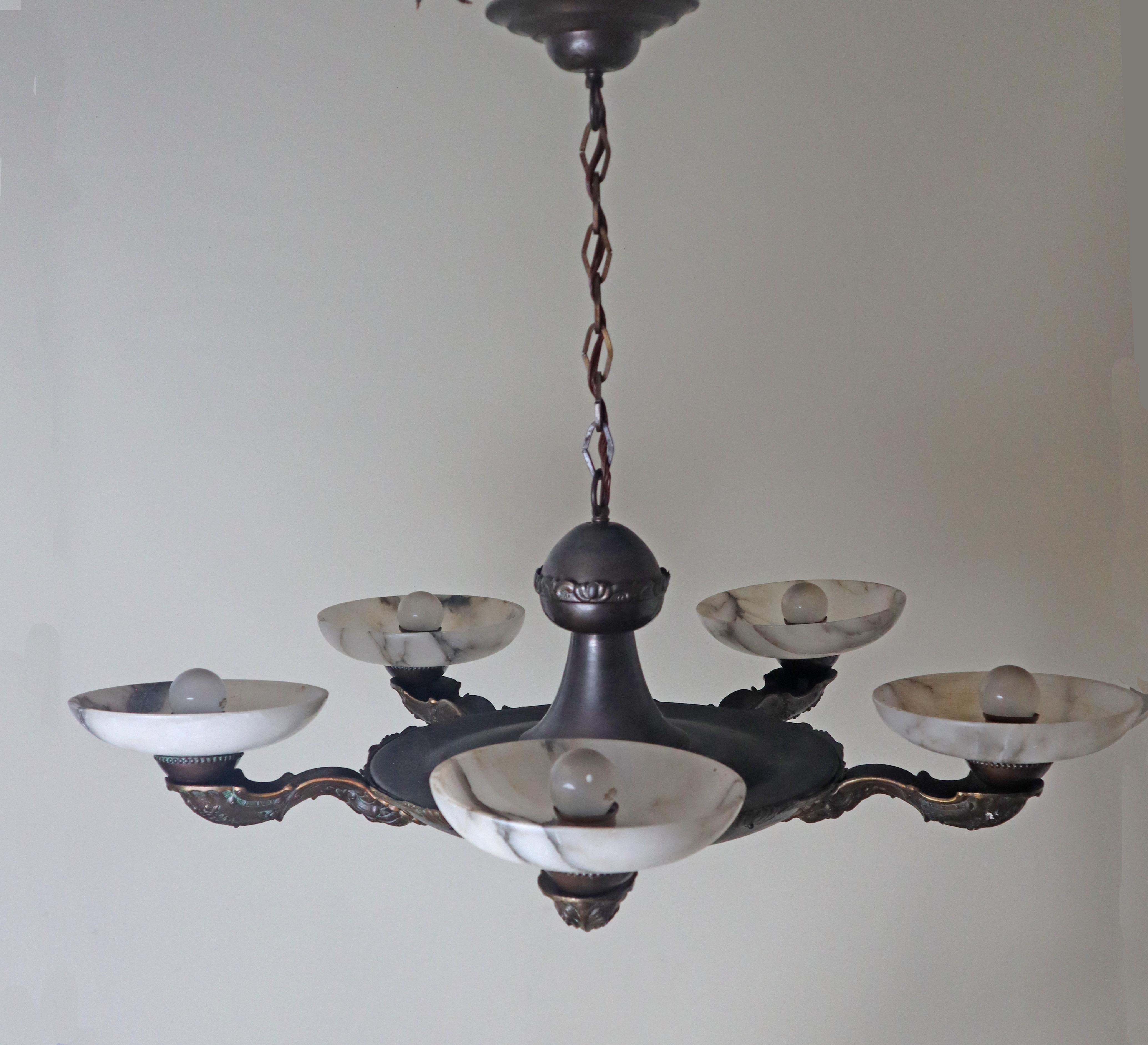 Esta elegante lámpara Art Déco, con sus cinco bellos cuencos de alabastro, atraerá todas las miradas. El armazón de la lámpara es de latón bronceado, y destaca la encantadora y auténtica pátina que se ha formado a lo largo de casi un siglo. Los