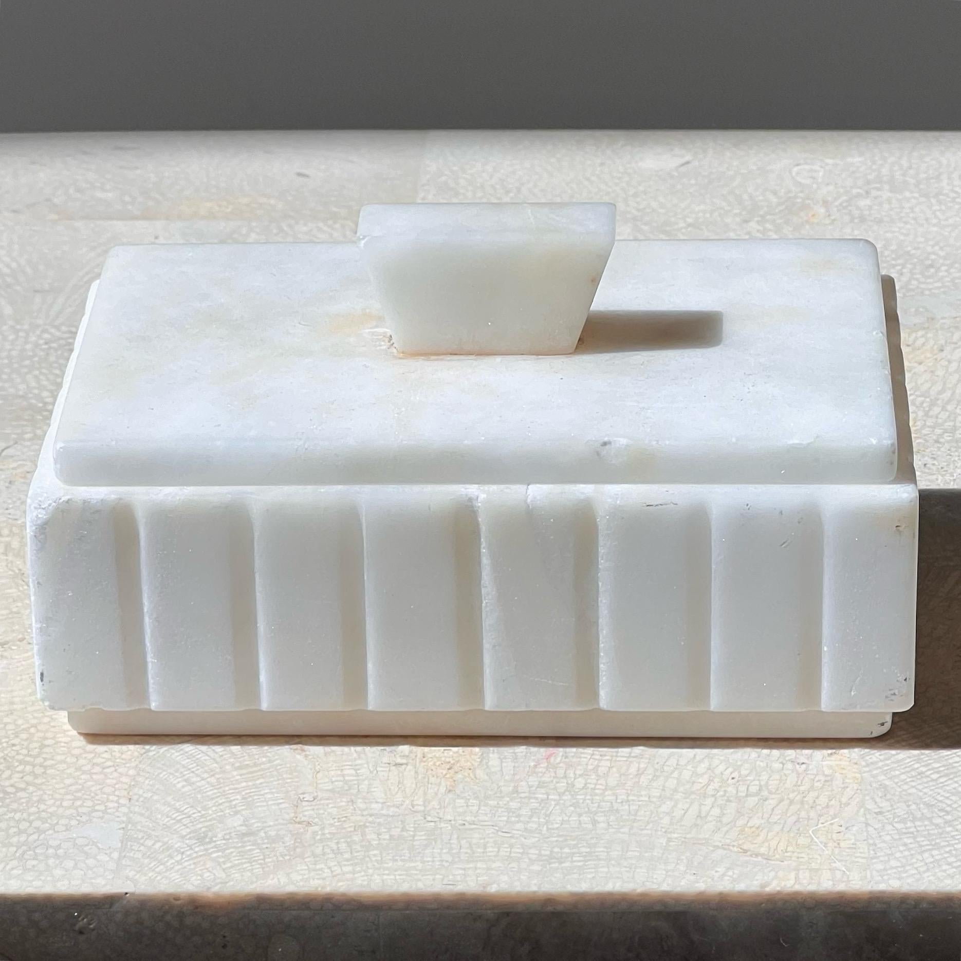 A lovely off-white alabaster trinket box, early to mid twentieth century. Probably from France or Italy. Featuring hand-carved “pin-stripes” along the edges of the body, and a geometrical top lid, this piece is at once and charming and unique. In