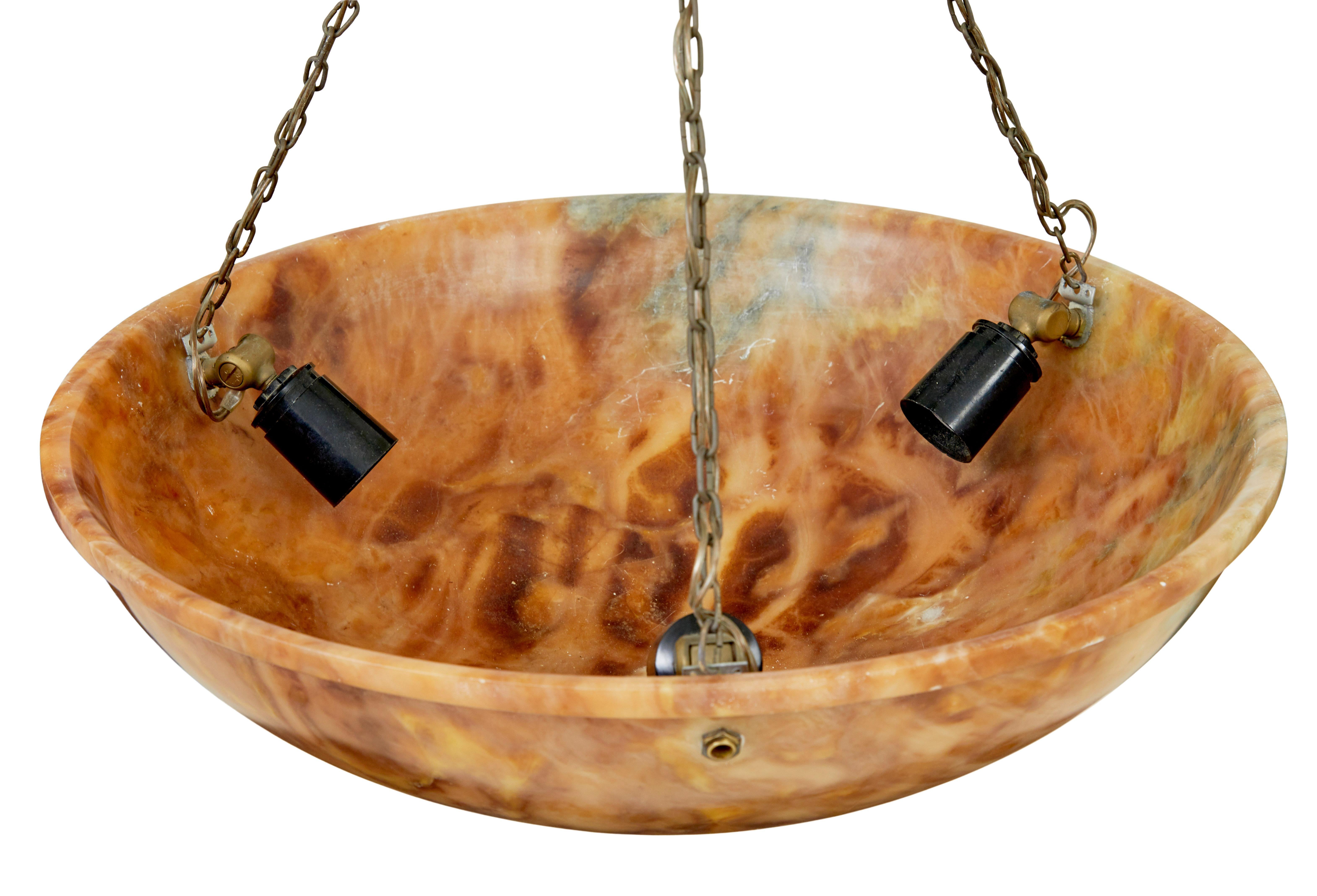 Art deco alabaster hanging dish light circa 1930.

Simple but elegant deco period ceiling pendant light.  Circular bowl with lipped edge, carved to show the natural stone colours of oranges and green veining.  Fitted with 3 bulb holders and