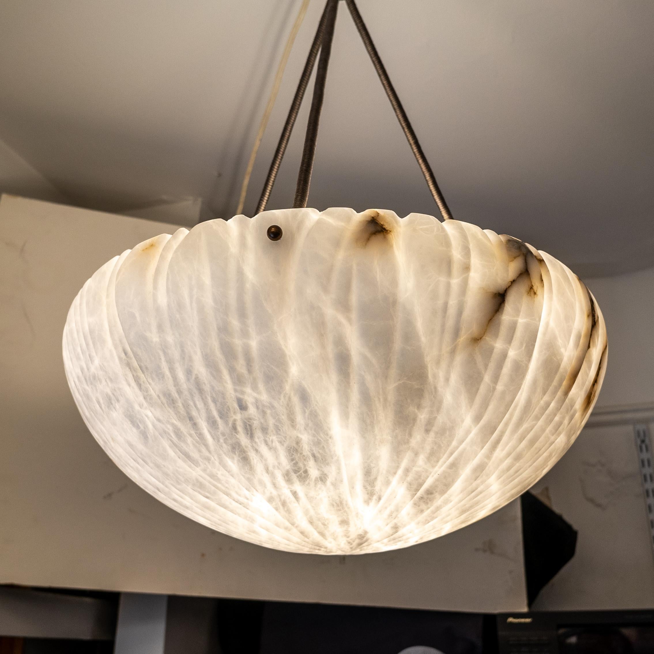 Reflecting the revival of organic motifs during the late Art Deco era, this ceiling fixture embodies a return to nature's embrace. Encased within a gracefully carved reedbed, the iconic bowl-shaped alabaster shade exudes timeless sophistication.