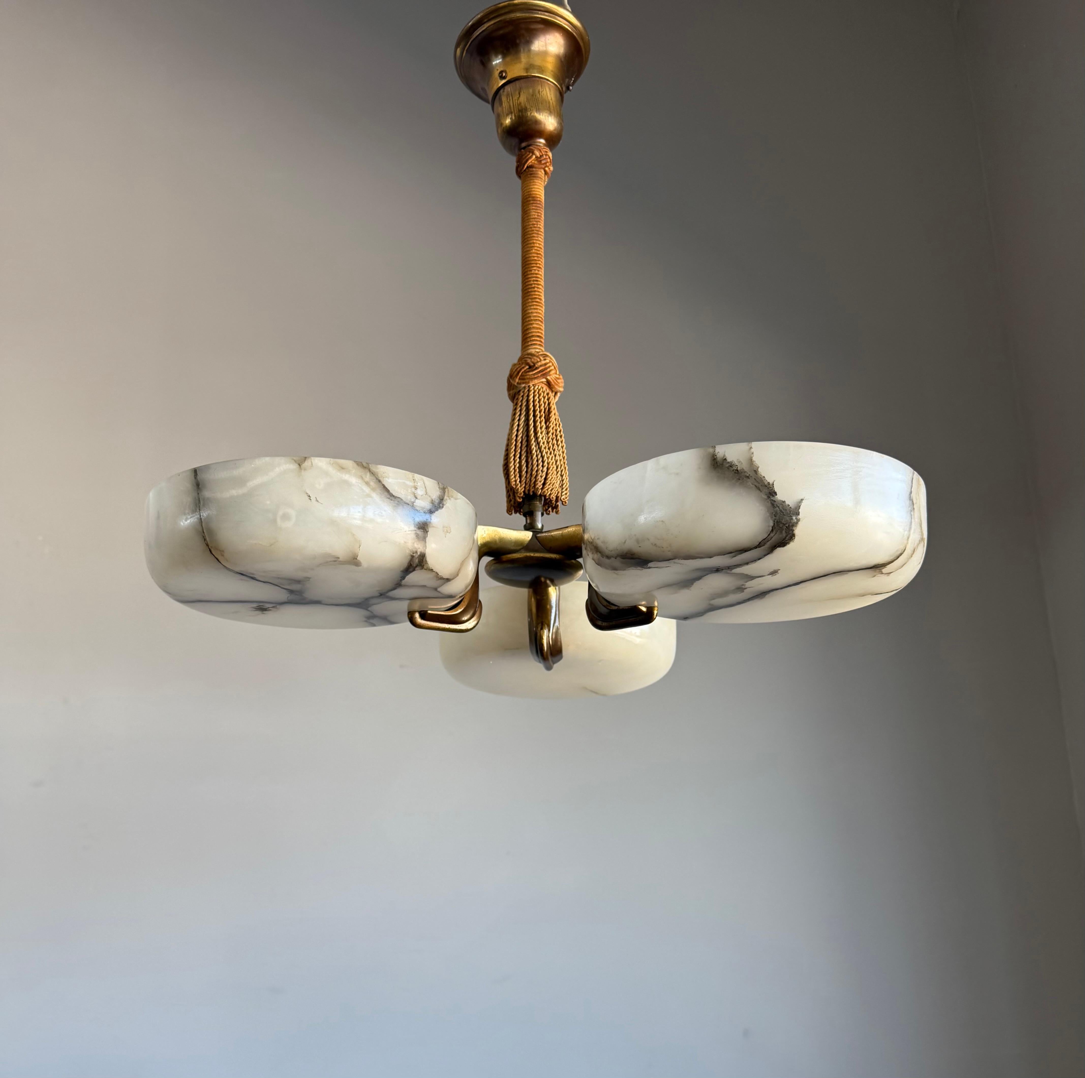 Stunning and rare Art Deco alabaster chandelier, from early 20th-century, Italy.

This exceptional chandelier stands out for its unusual design, with three hand-carved alabaster shades positioned closely around the center, a rare departure from the
