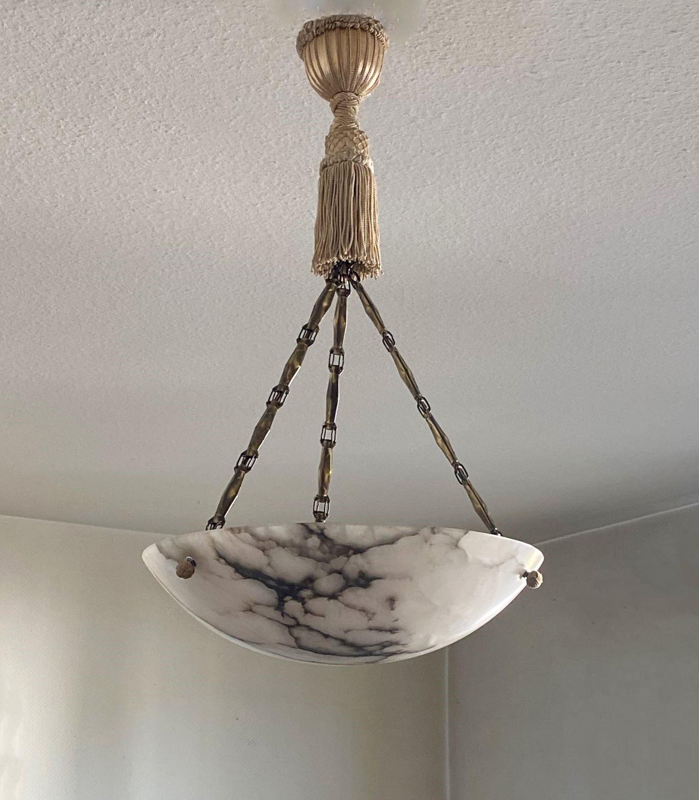 A beautiful Arte Deco alabaster pendant / light fixture, France, 1910-1920. Large polished alabaster with black veins shade, original brass chains connecting to original handmade silk tassel fringe rope and tassel canopy. It takes a E27 screw bulb