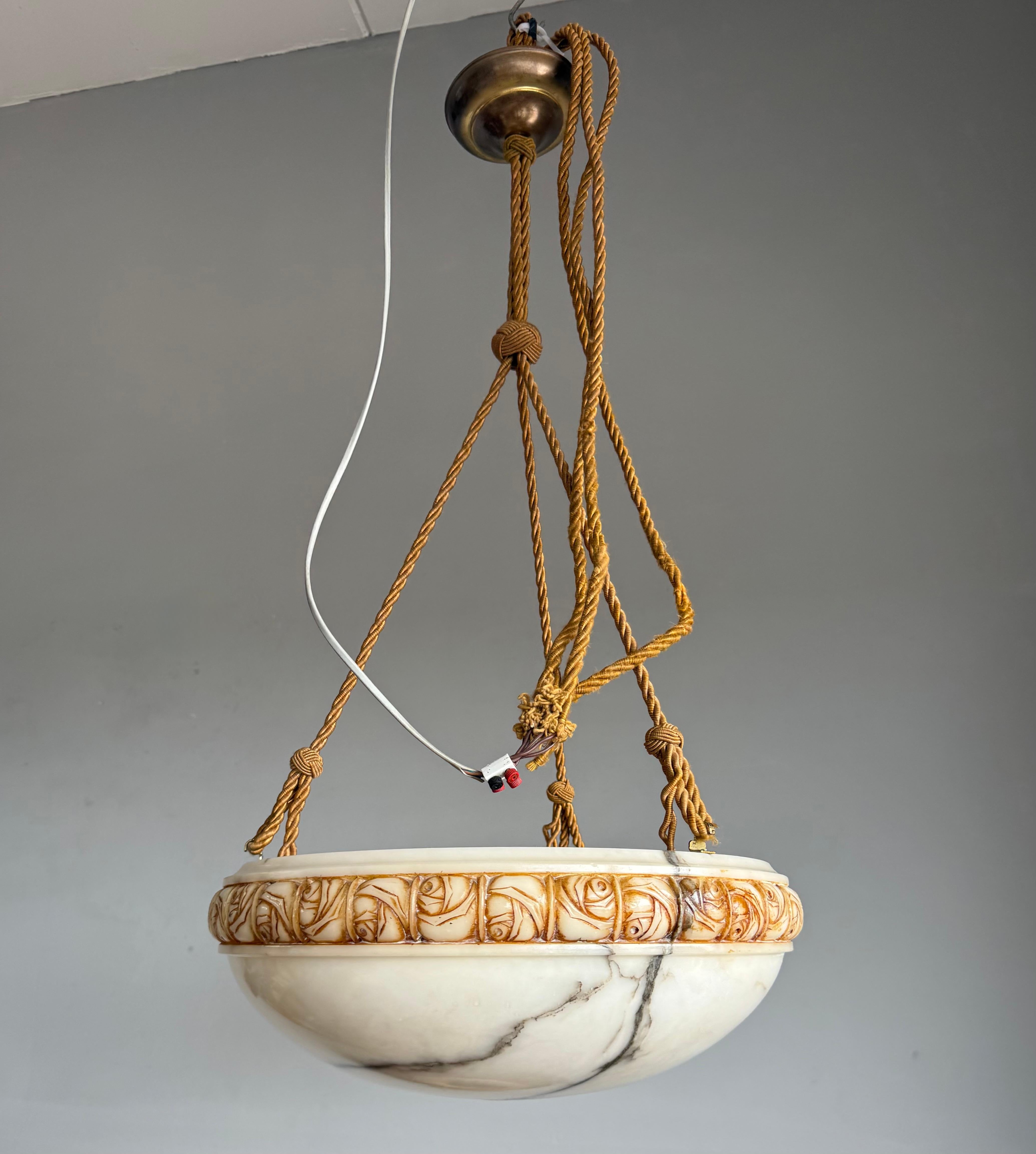 Exquisite French Art Deco white alabaster pendant with carved rose motif and rope suspension, 18.5” Diameter.

A masterfully crafted French Art Deco alabaster pendant light dating from the golden heyday of 1920s-1930s design. The bowl-shaped shade
