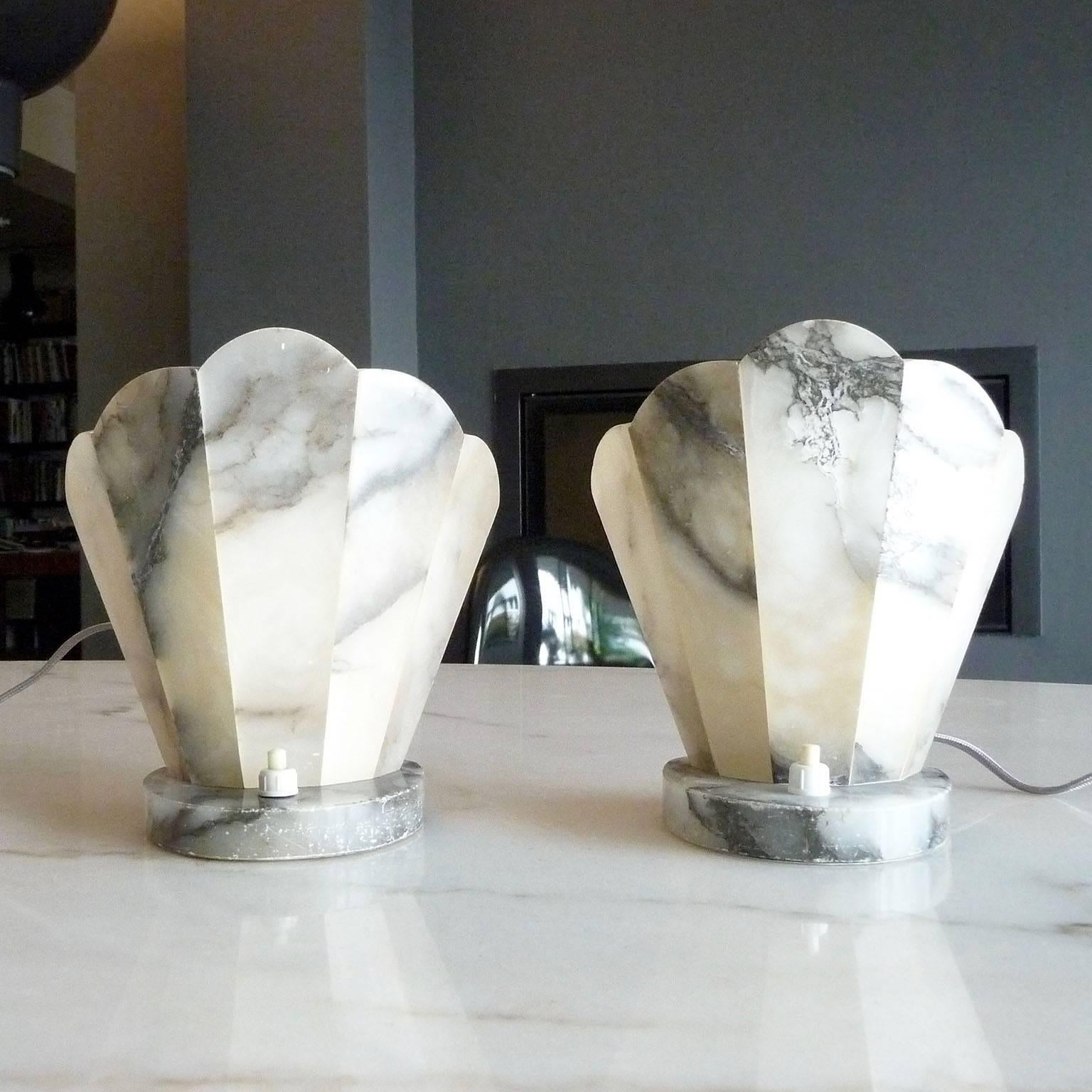 Pair of French Art Deco table lamps or bedside lamps, made of alabaster, round bases, flattened front, fan shaped rear wall, electrified, circa 1930.
Good used condition with normal wear of time.

Dimensions: 
Height 17 cm (6.69 in.)