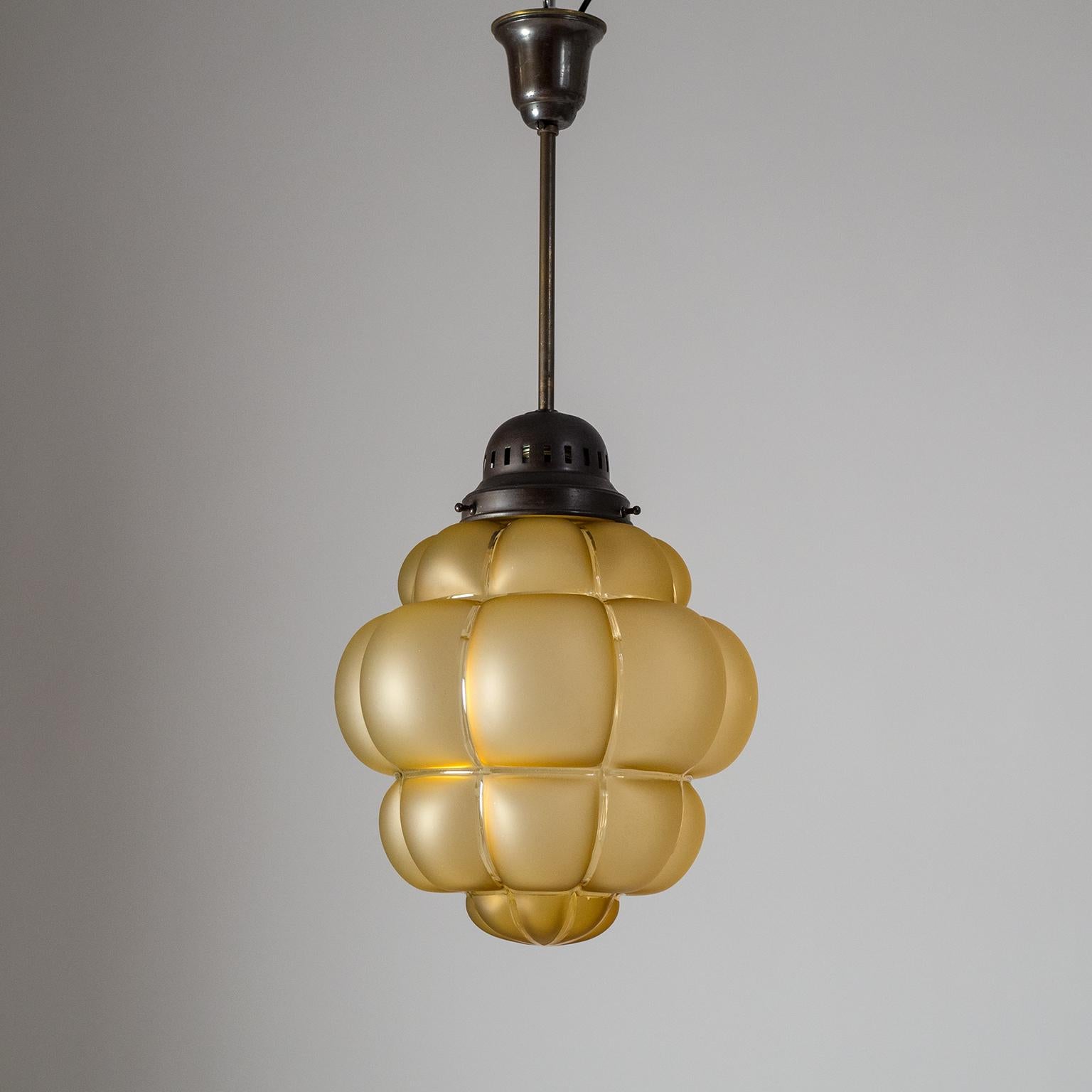Very unique Art Deco pendant from the 1920s. A rare 'bubble' shaped amber glass diffuser satinated with clear stripes is suspended by dark patinated brass hardware. Very nice original condition. One original brass and ceramic E27 socket with new