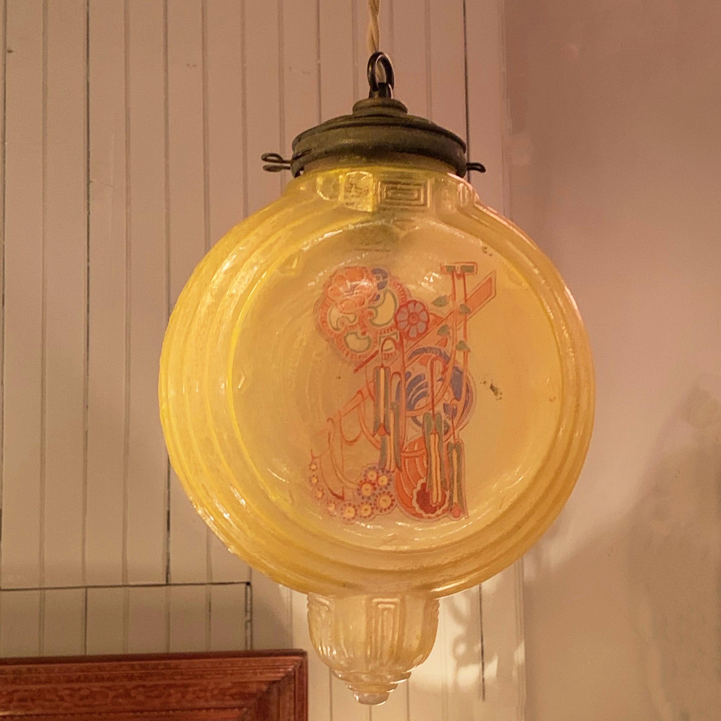 Art Deco pendant light features a molded, crackled, amber glass shade with painted chinoiserie design on both sides with brass fitter and canopy. The pendant is wired with 50 inches of braided beige cloth cord to accept up to a 100 watt bulb.