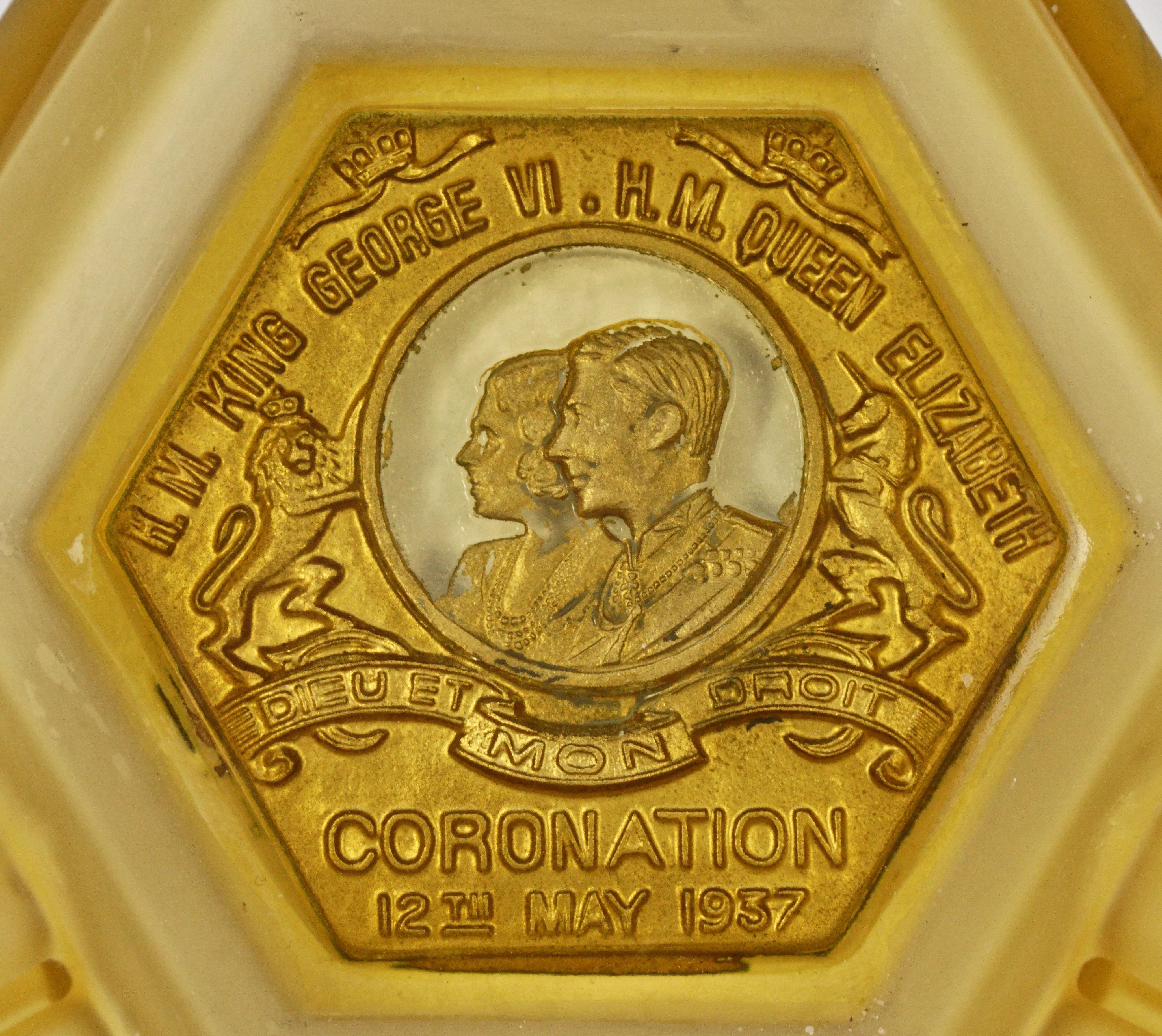 Frosted amber glass ashtray to commemorate the Coronation of King George VI and Queen Elizabeth, 12th May 1937, and featuring a golden embossed design of the King and Queen. The ashtray has a classic Art Deco shape, and has grooves for cigarettes
