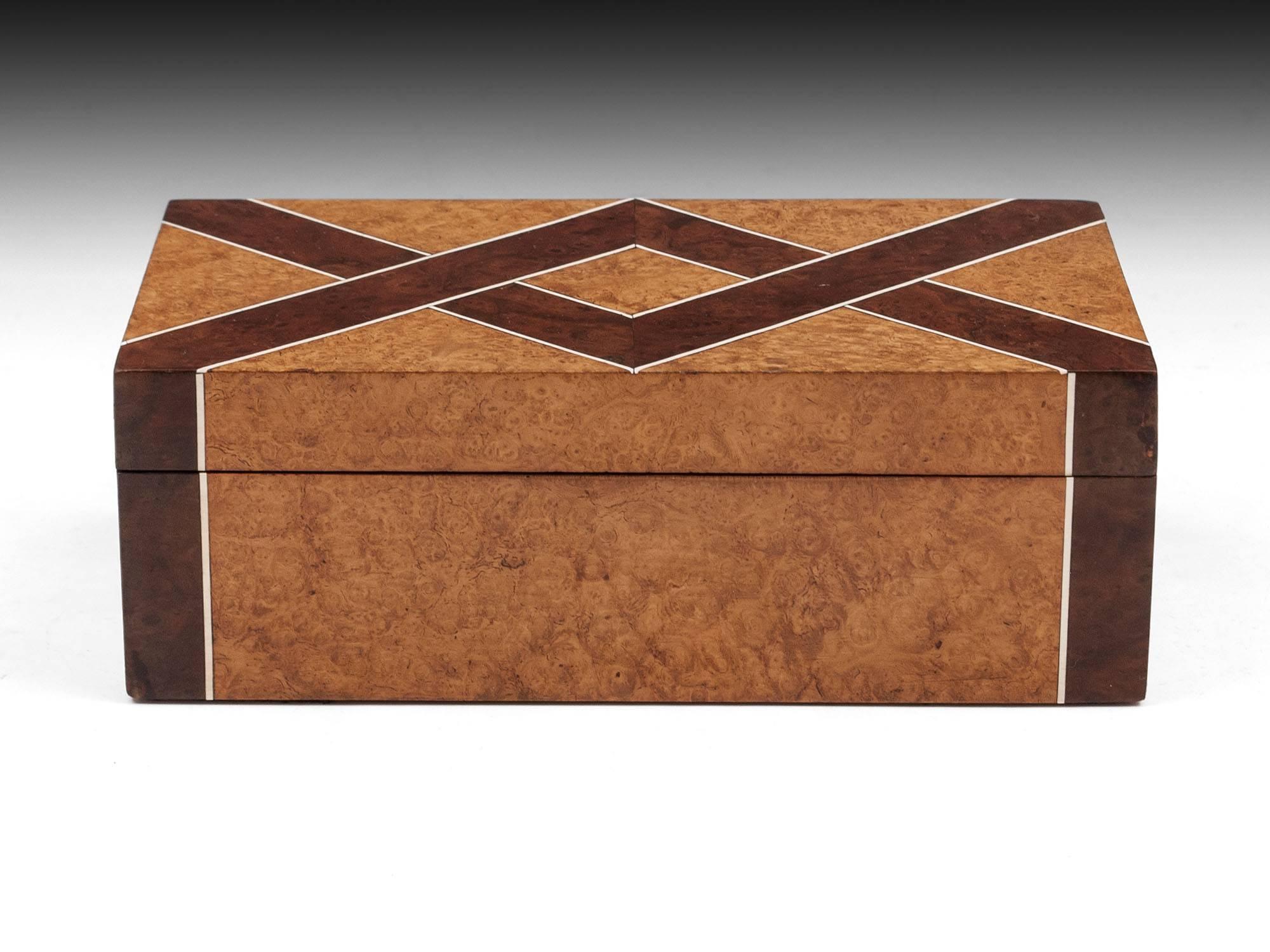 Striking Art Deco trinket box veneered in amboyna with bands of burr walnut with bone inlay either side. 

The interior is cedar lined.