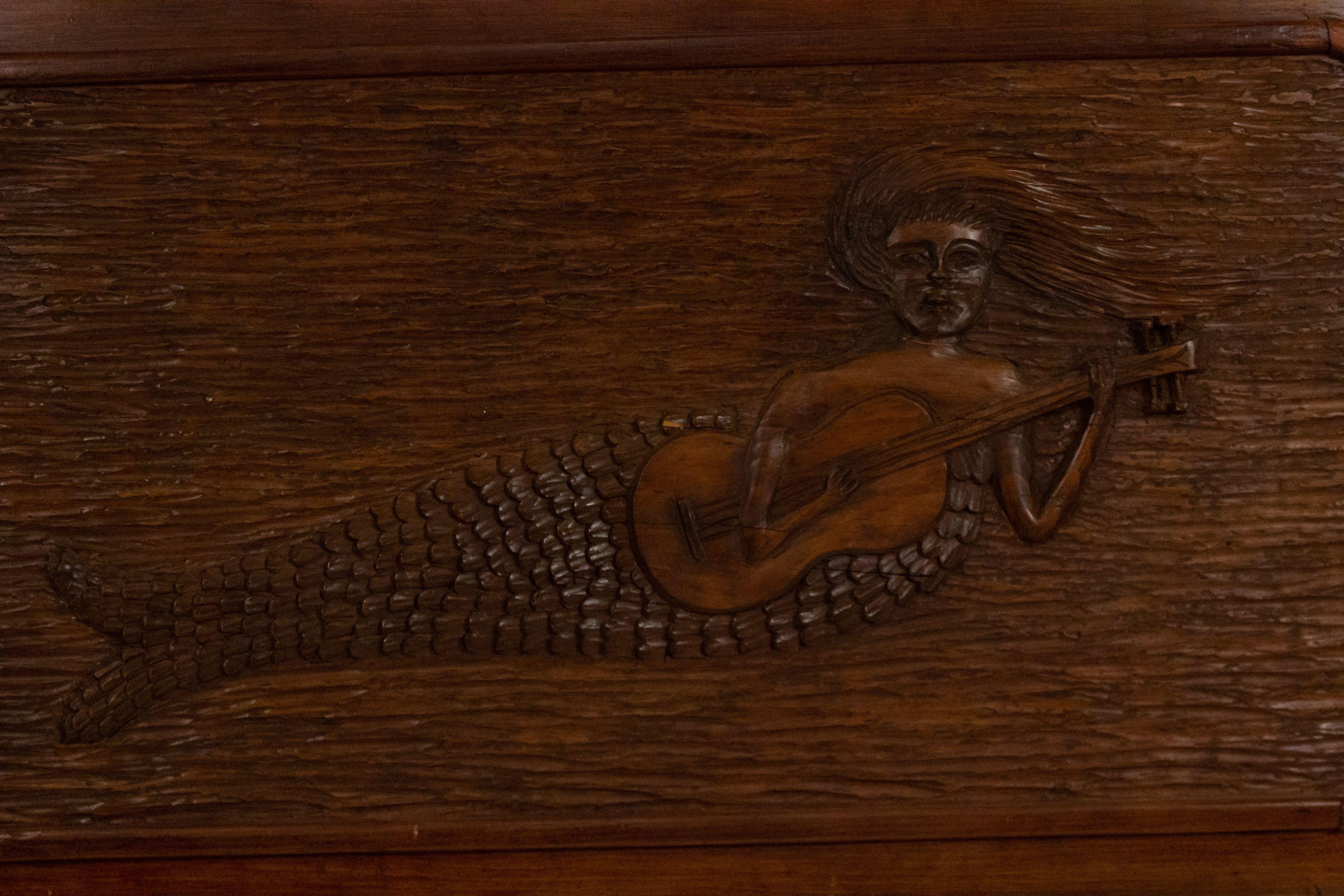 Art Deco American carved walnut wall plaque of a mermaid playing a guitar with a carved scroll top.
  