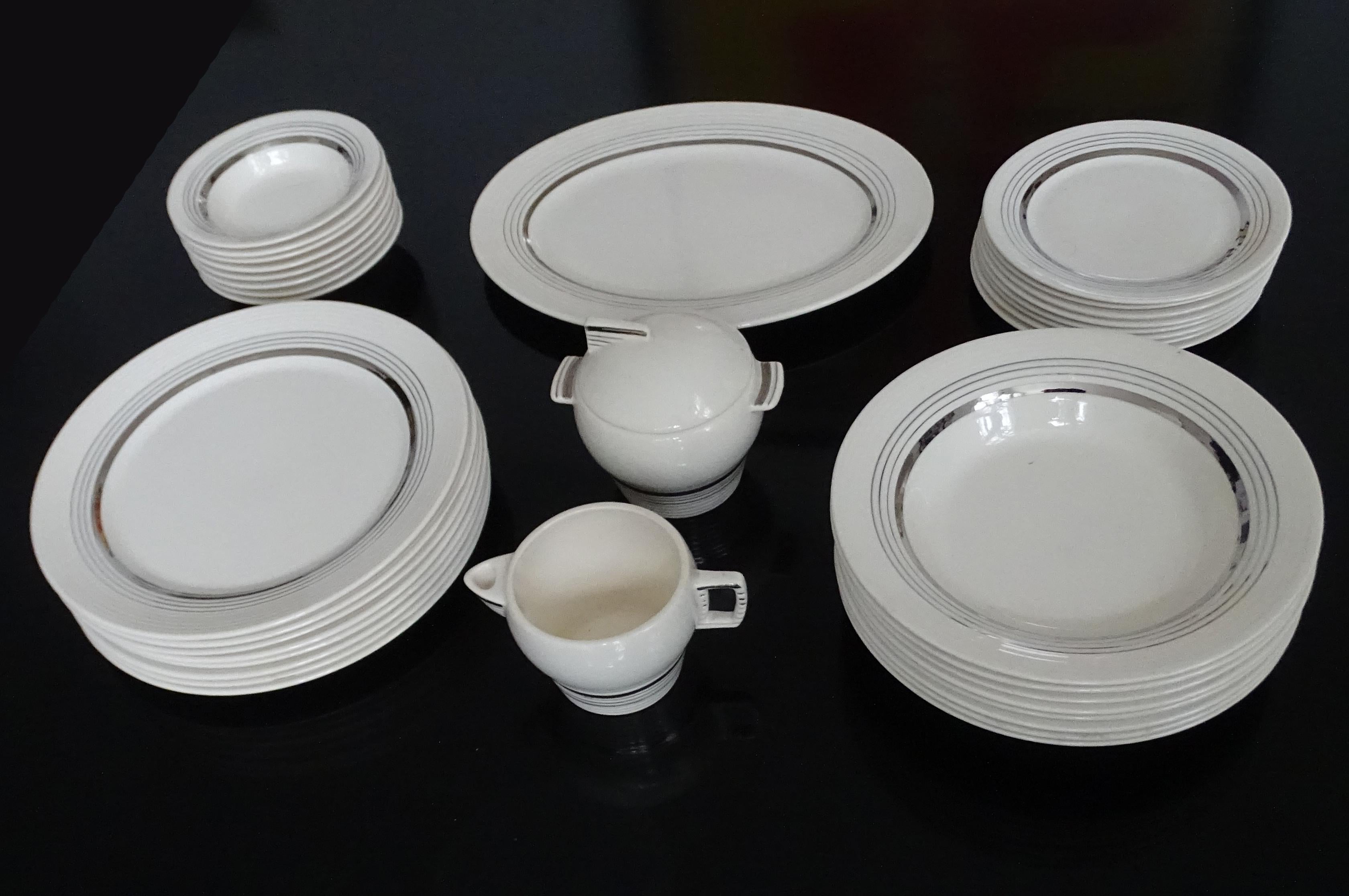 Extremely rare Art Deco China dining set manufactured by American Limoges, circa 1935,
This set is from the Triumph Silver Age serie and features applied 22-karat white gold concentric rings.

The set comprises: 

6 main course plates 24 cm / 9.5 in