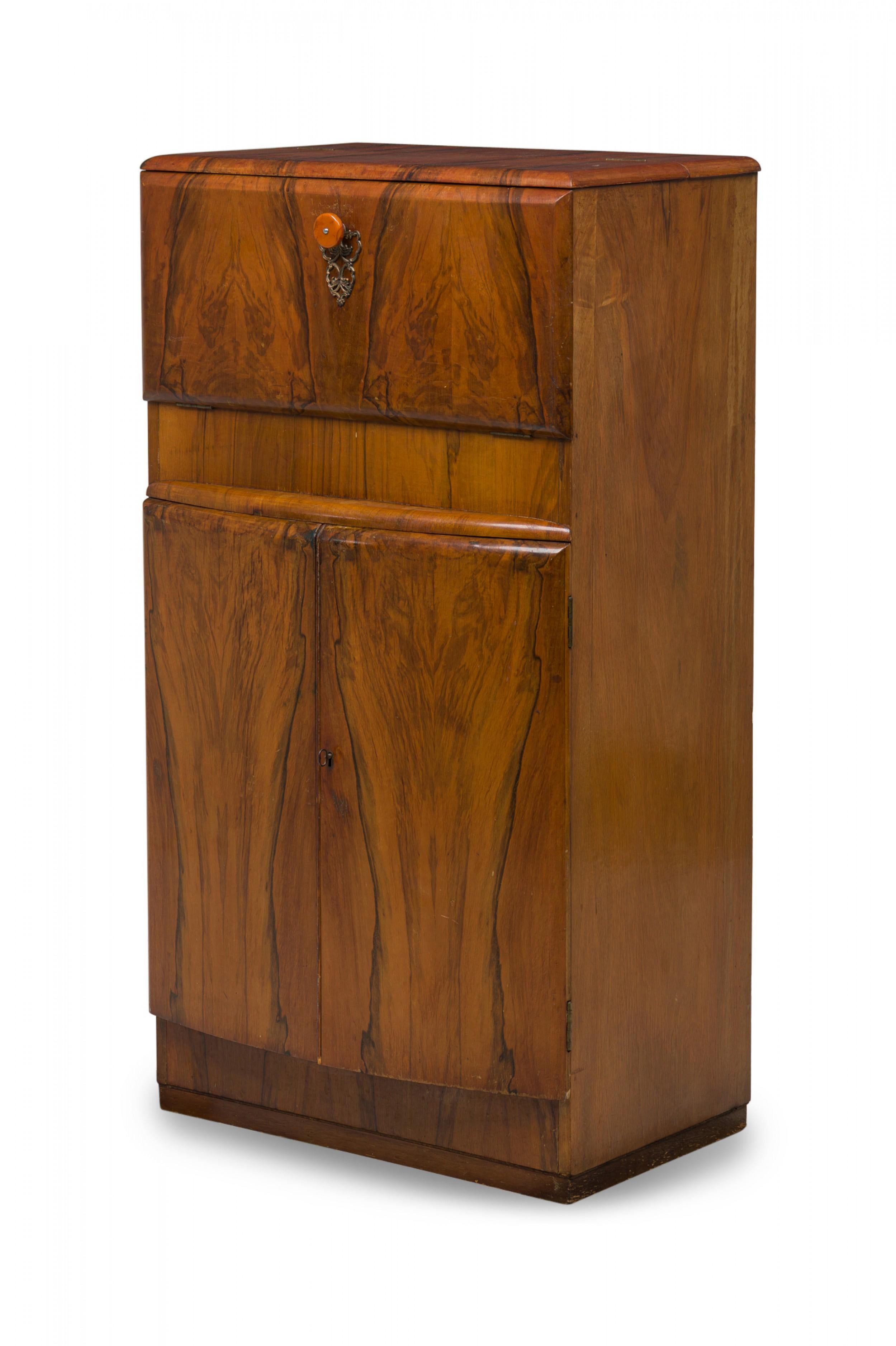 Art Deco American bow front matchbook veneered rectangular bar cabinet with a hinged top dropdown drawer (with scroll & foliate brass escutcheon plus original bakelite signature pull) over a drum bottom section's pullout doors hide

Condition: Good;