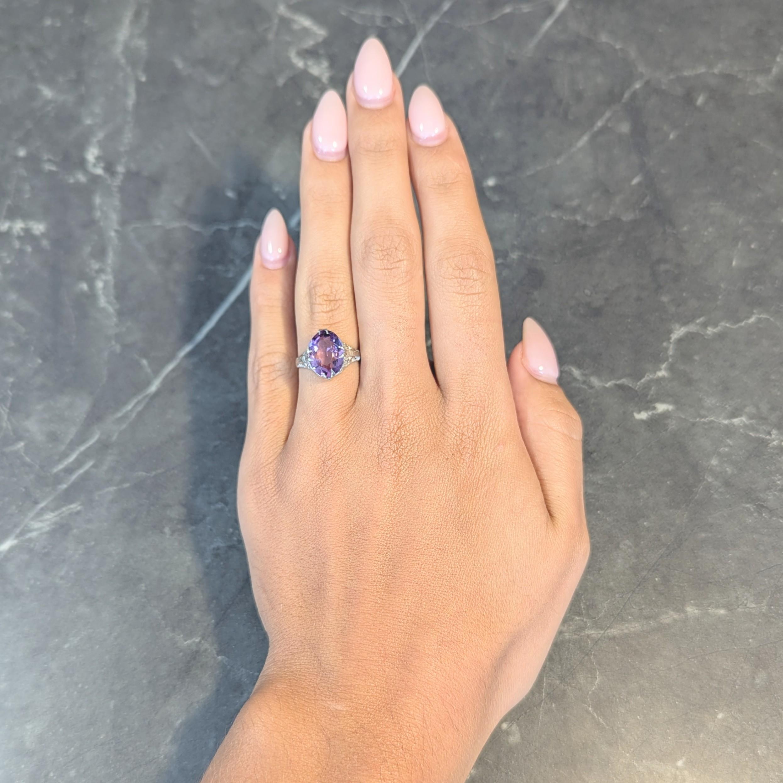 Centering an oval-shaped mixed cut amethyst measuring 9.0 x 12.0 mm 
Transparent medium purple in color and set with split talon prongs
Featuring a pierced foliate motif filigree gallery with milgrain detail
Flanked by engraved wheat motif