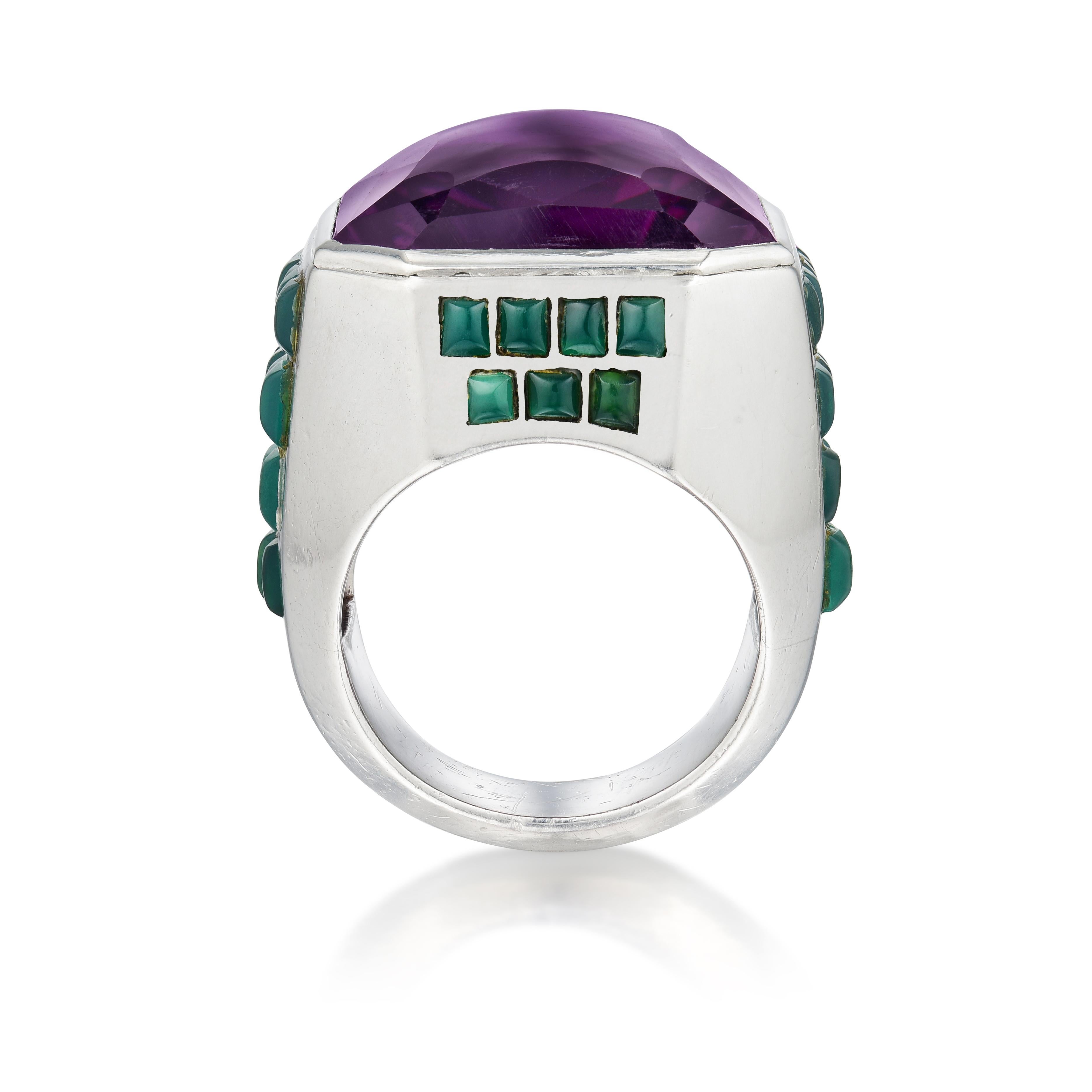 A ring bezel-set in the center with a modified step-cut amethyst, the shoulders and sides cascading with decreasing lines of bezel-set rectangular cabochon chrysoprase; mounted in silver, with French assay marks
• Maker’s mark for Grœné et Darde
•