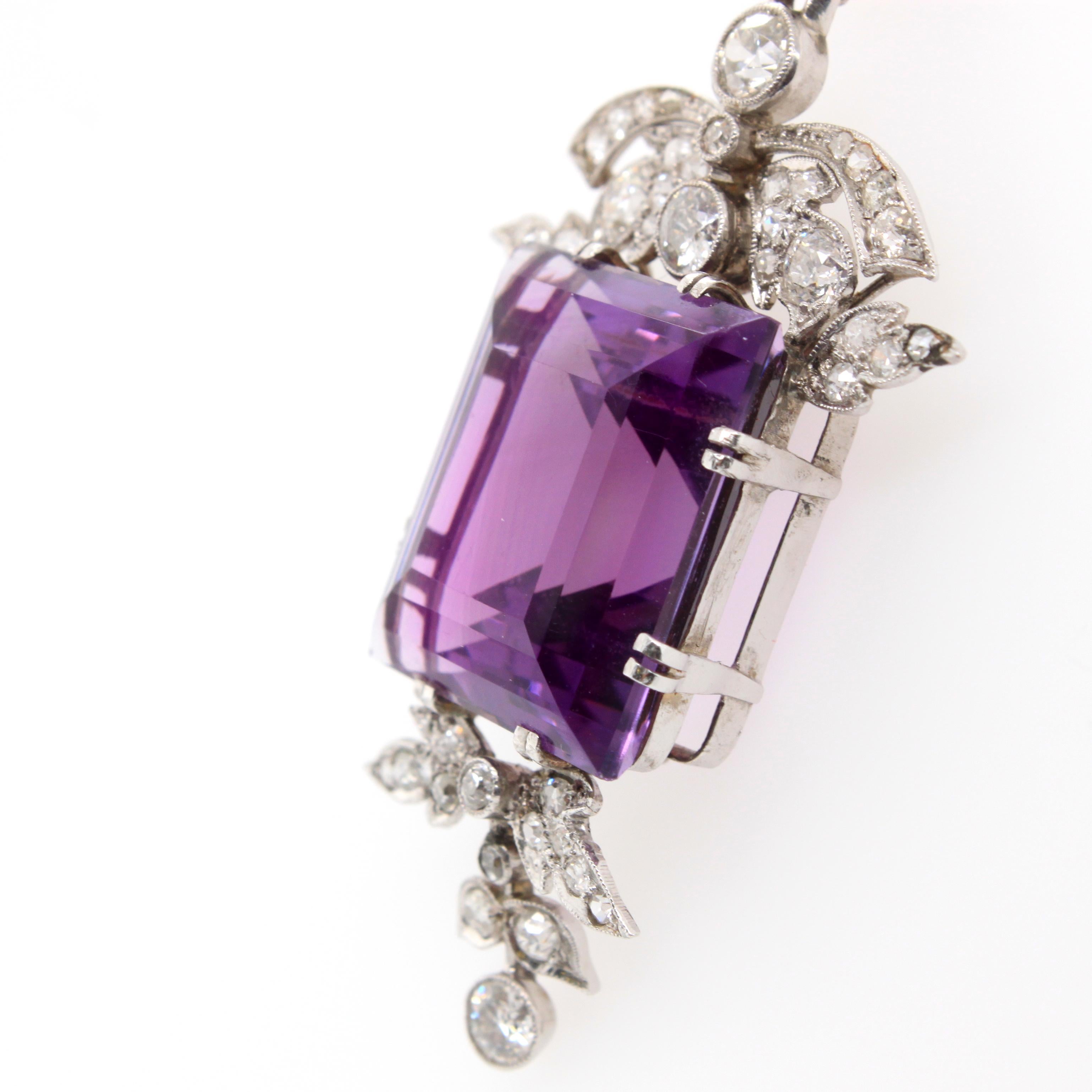 A puissant amethyst and diamond brooch/pendant, Art Deco, ca. 1930s. The square cut amethyst centres the jewel and has a deep Siberian purple colour, weighing approximately 20 carats. It is set between round brilliant cut diamonds in a floral motif.