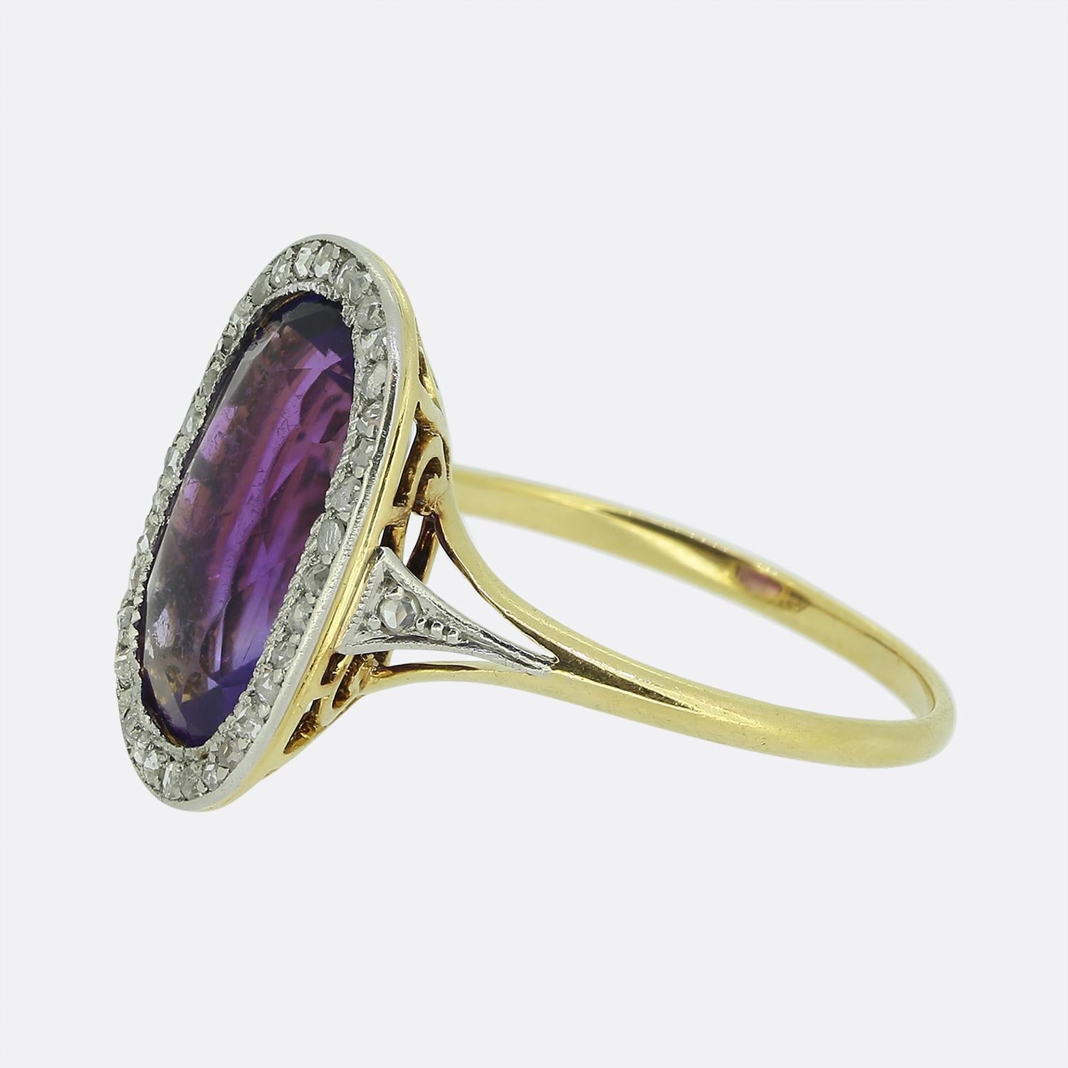Ecco uno splendido anello con ametista e diamanti realizzato durante l'apice del movimento Art Déco. Al centro del viso troviamo un'ametista ovale sfaccettata di forma allungata che possiede una ricca tonalità di colore viola reale. Questa pietra