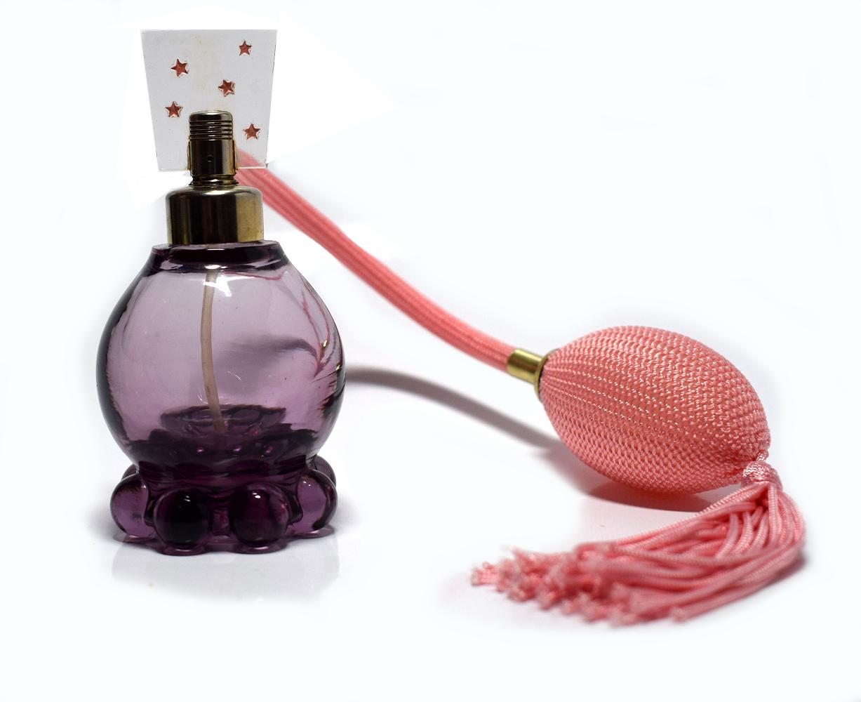 A delightful vintage 1930s amethyst glass perfume atomiser glass bottle with clear Lucite panel to the top with stars design. Very typical of the period. Gold tone metal top and pink atomiser bulb/puffer with tassel all in working order and super