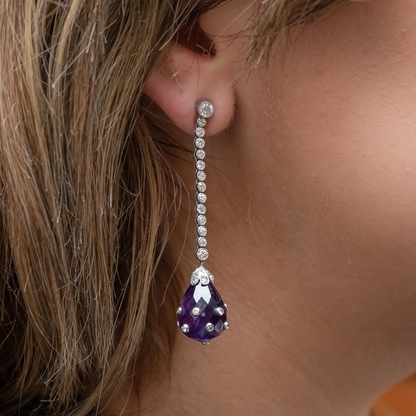 A pair of Art Deco, amethyst and diamond earrings, with Edwardian-cut diamonds in the tops, with thirteen, round brilliant-cut diamonds, in each, in articulating, millegrain edged, rub over settings, with caps set with rose-cut diamonds and
