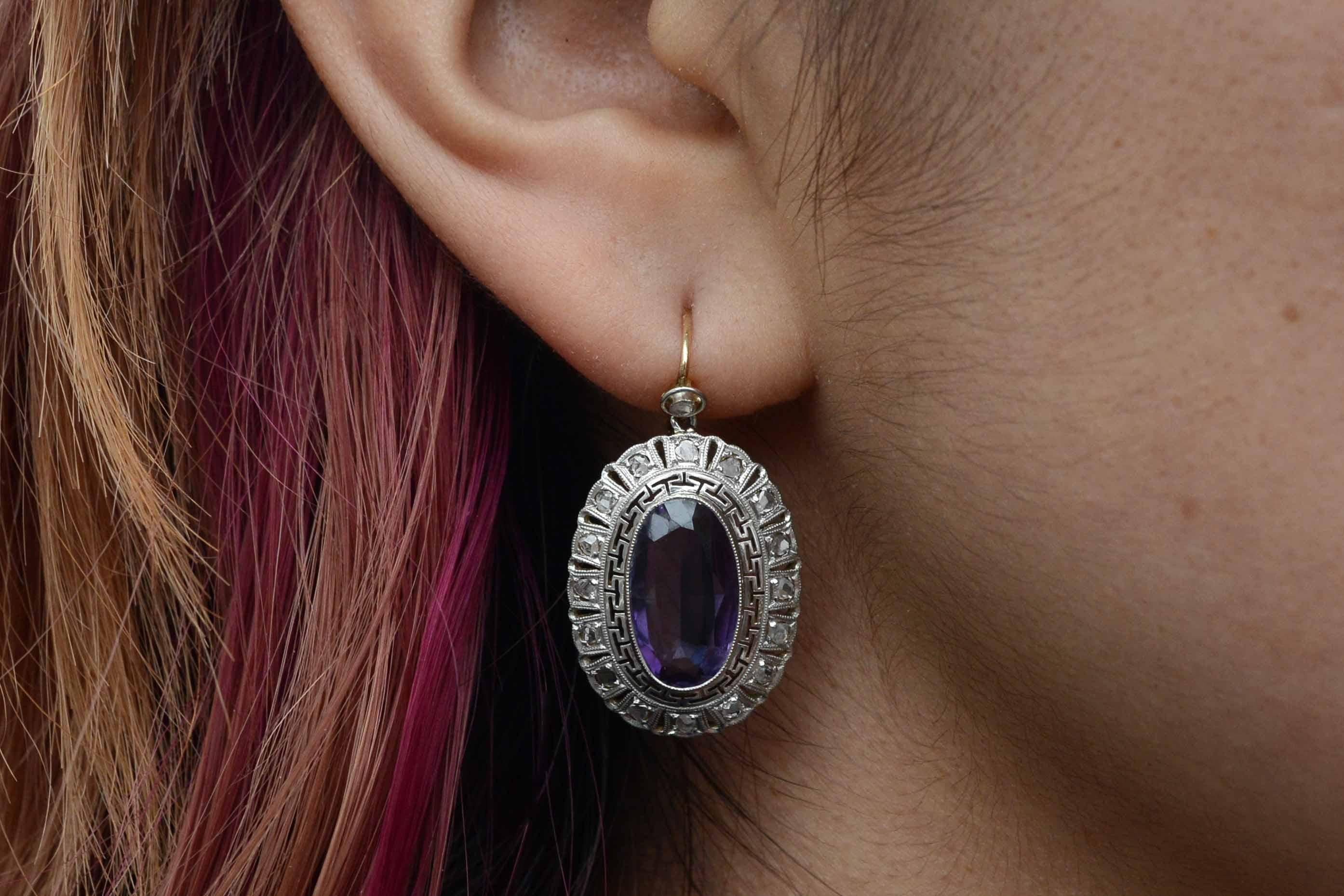 A most dramatic pair of Art Deco dangle earrings that drop so seductively and sweep your shoulders with a wonderful violet amethyst. Surrounding the velvety gemstone is a most alluring Greek key design which is framed with delicate rose cut diamonds