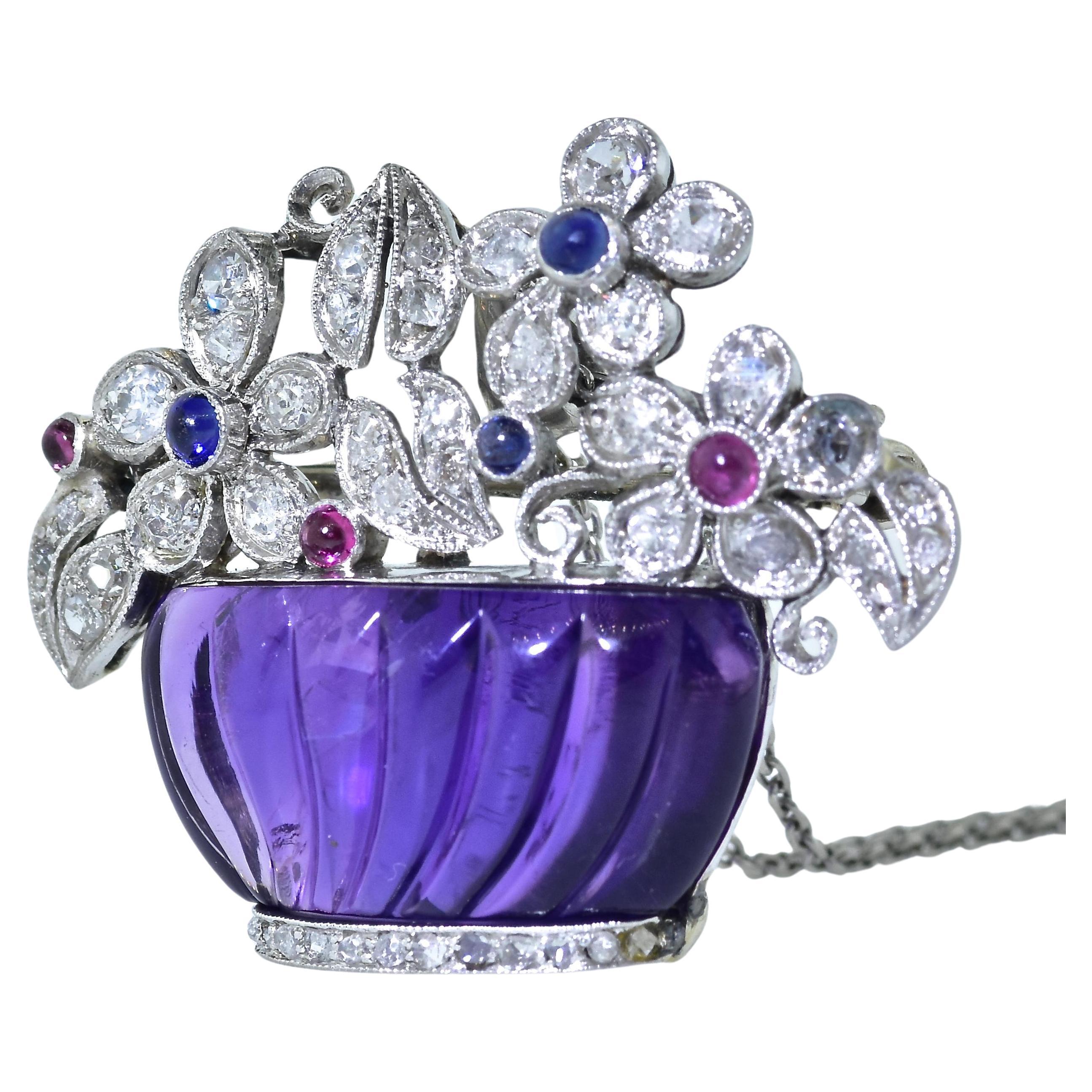 Art Deco pendant with a carved natural amethyst (probably Siberian because of the presences of reddish undertones), creates a platinum, diamond, sapphire and ruby basket of flowers, 
this charming piece, with a flip up/flip down bale has 43 small
