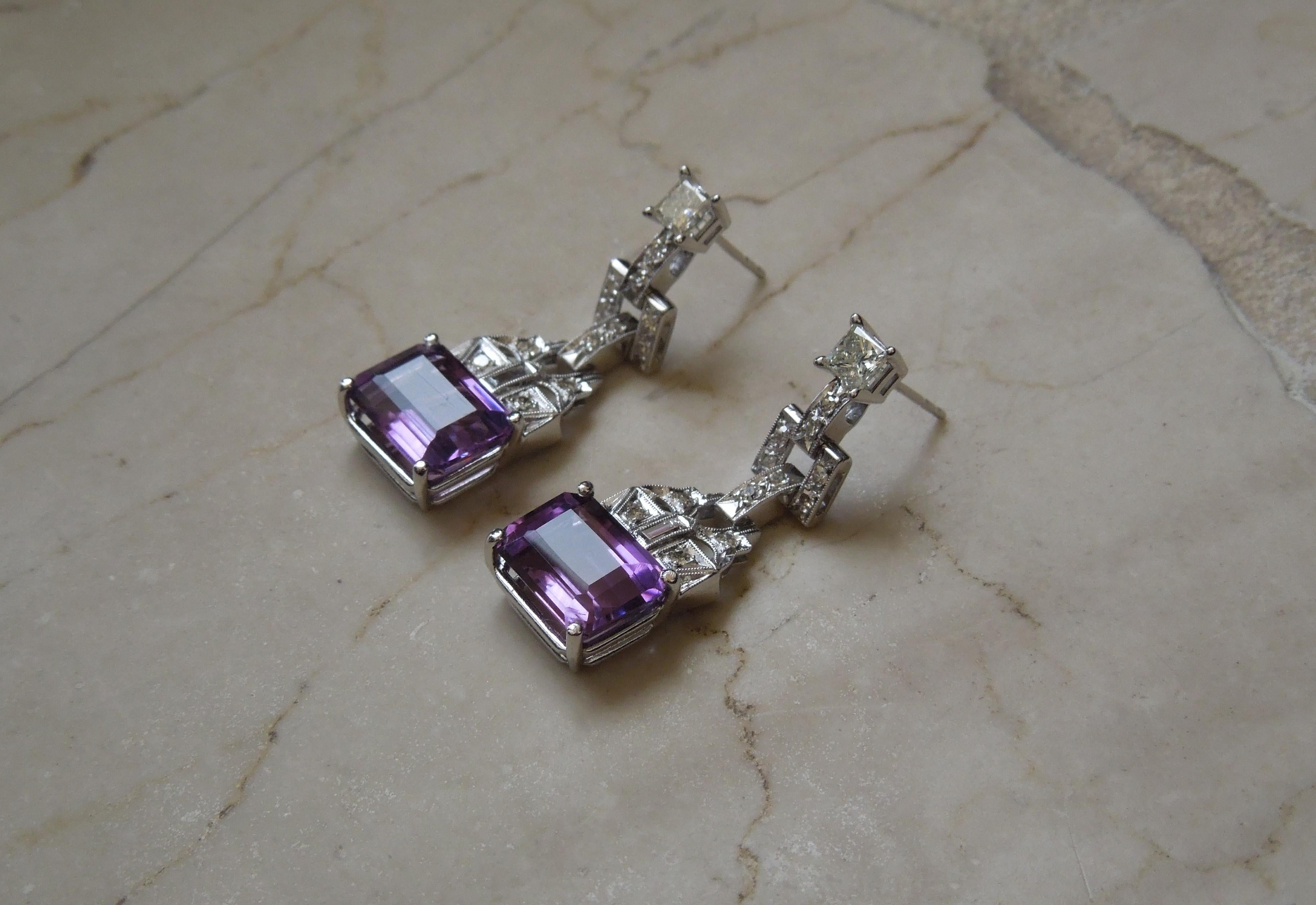 Constructed of a combination of 14 Karat White Gold & Platinum - Featuring 2 Focal Emerald cut Intense Purple Amethysts totaling approximately 6.59 carats measuring 102mm-10.8mm in length x 7.5mm in width, each secured in a 4-Prong Setting.  
Each