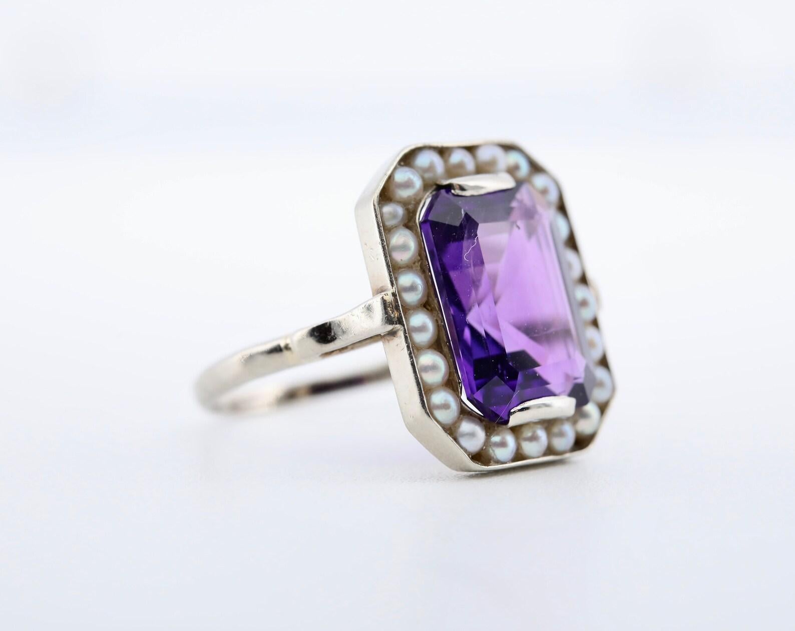 A handmade Art Deco period natural pearl and amethyst halo style ring.

Centered by a vivid purple amethyst measuring 12mm by 9mm, and weighing approximately 5 carats.

Encircled by a halo of natural cream colored saltwater pearls measuring 2.5mm