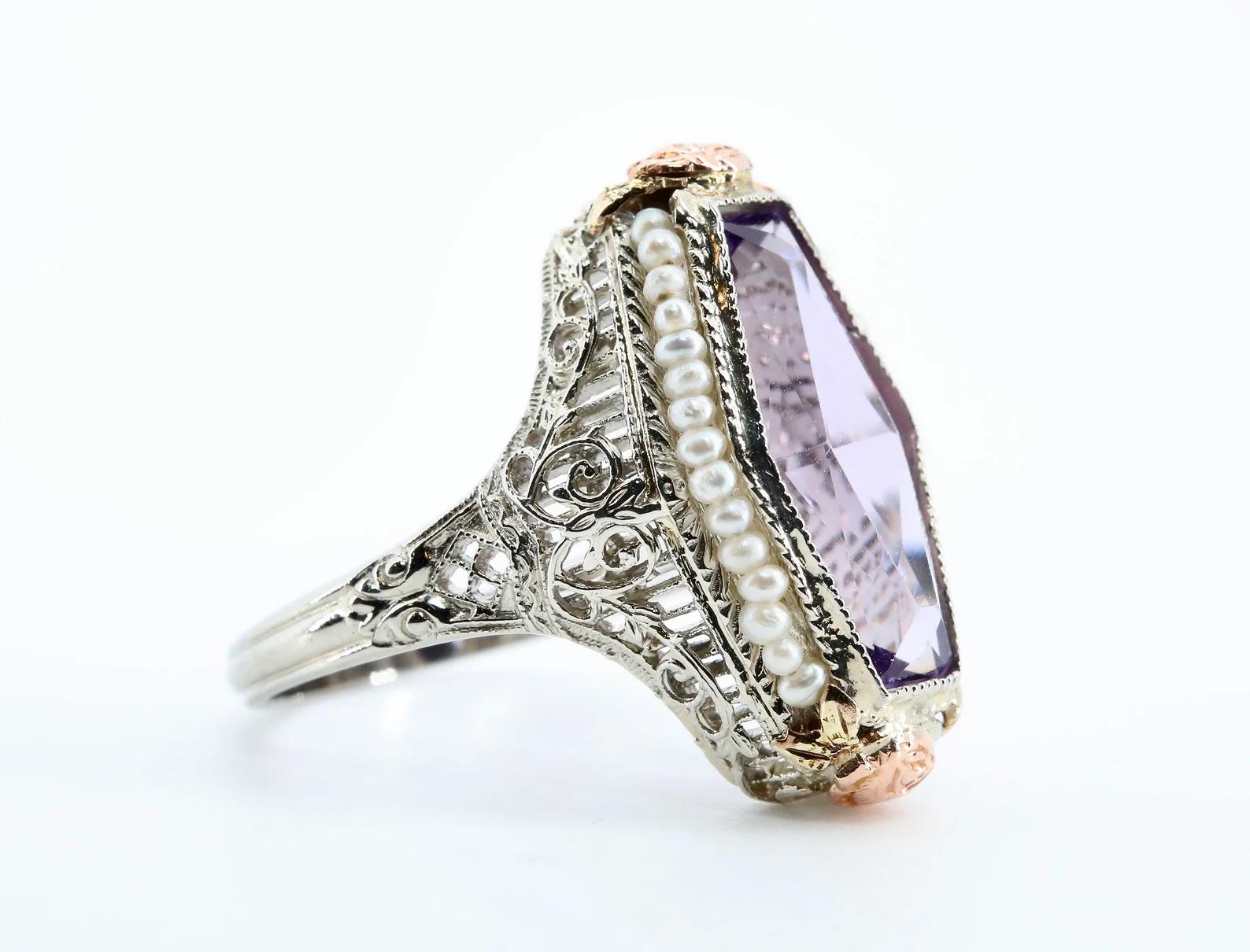 An original Art Deco period amethyst, and seed pearl filigree ring in 14 Karat white gold. Centered by an elongated hexagon amethyst set in a miligrained bezel setting. Framing the amethyst are natural seed pearls strung on a gold wire. Accenting