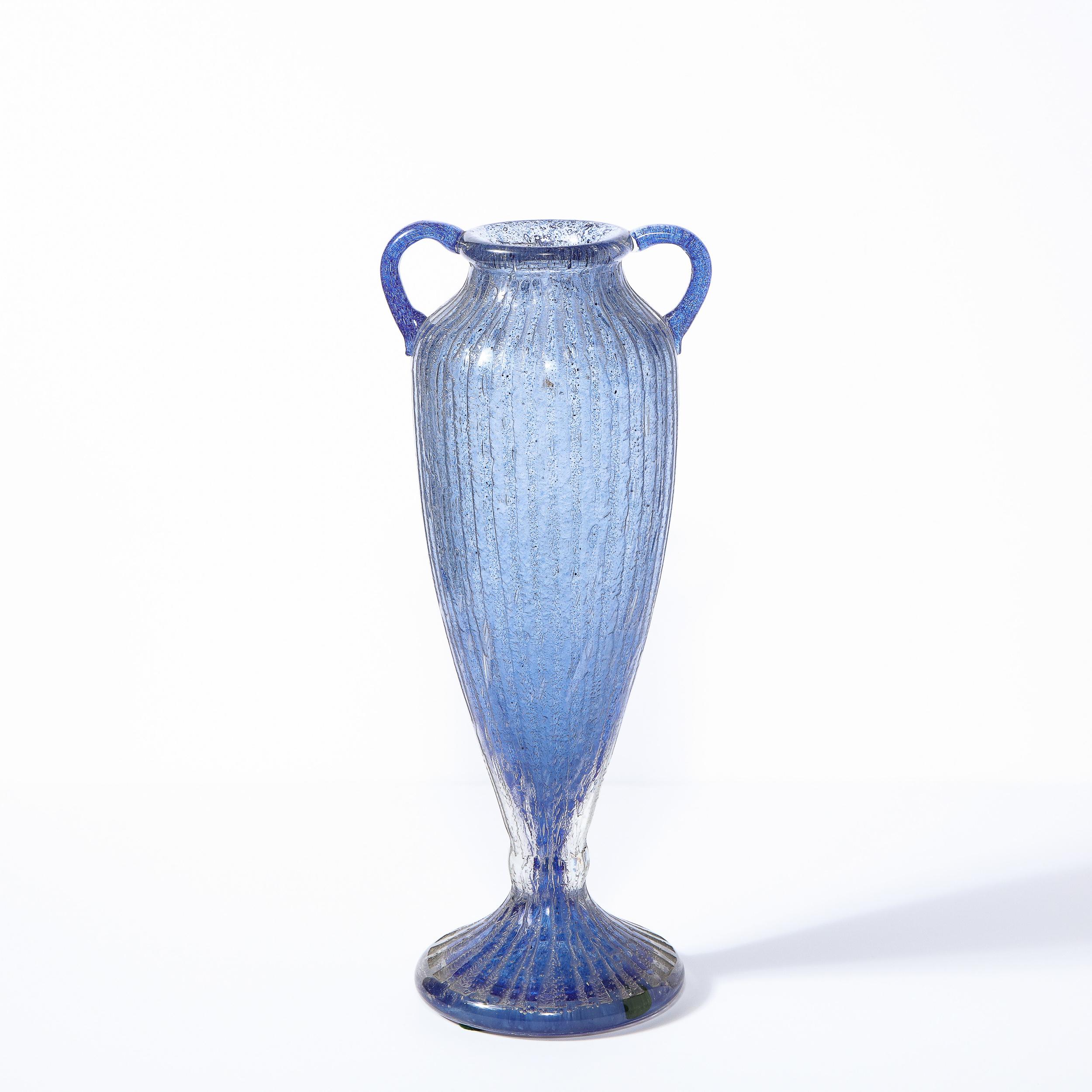 This refined Art Deco amphora vase was realized and signed Nancy Daum in France circa 1925. It features an undulating body flanked on its neck by two rounded handles- all in mottled lilac glass wrapped by a channeled translucent glass exterior. With