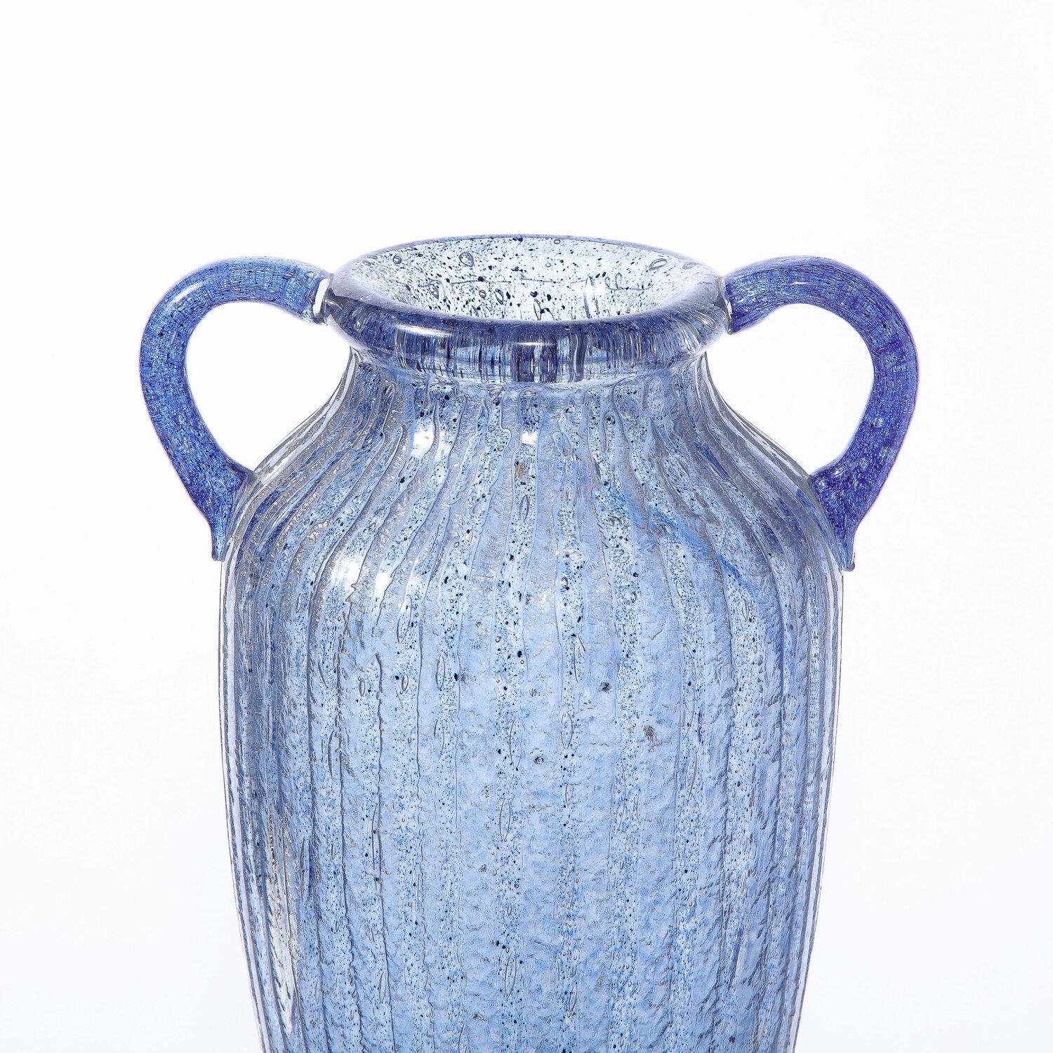 Ce vase amphore raffiné de style Art déco a été réalisé et signé Nancy Daum en France vers 1925. Il présente un corps ondulé flanqué sur le col de deux poignées arrondies, le tout en verre lilas tacheté enveloppé d'un extérieur en verre translucide