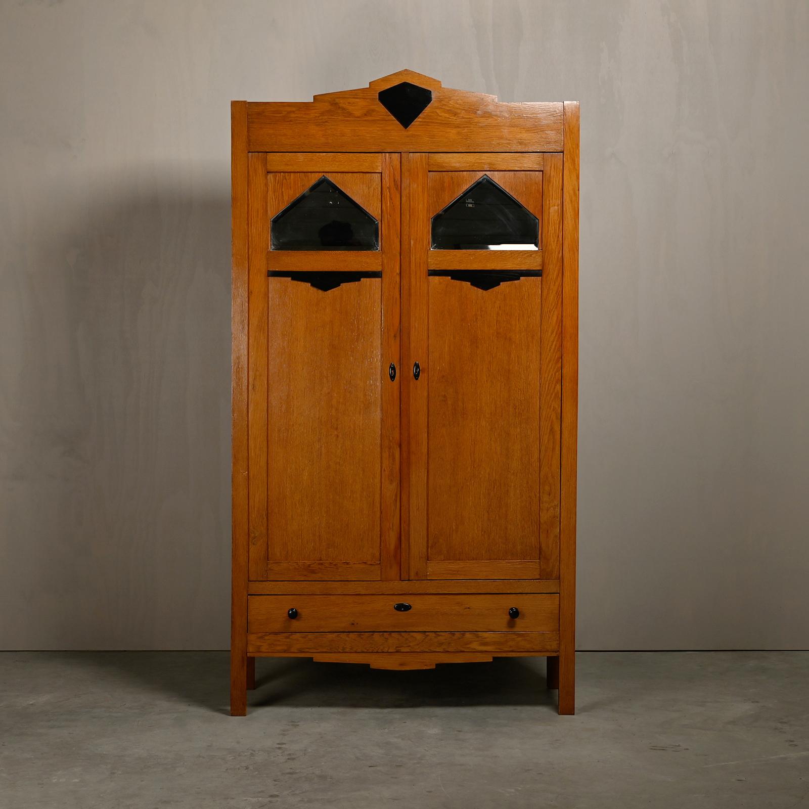 Magnifique armoire ou penderie Art déco de l'école d'Amsterdam des années 1930. Quatre étagères et un tiroir avec le miroir biseauté d'origine dans les deux portes et des éléments décoratifs. En bon état d'origine, avec une légère usure due à l'âge