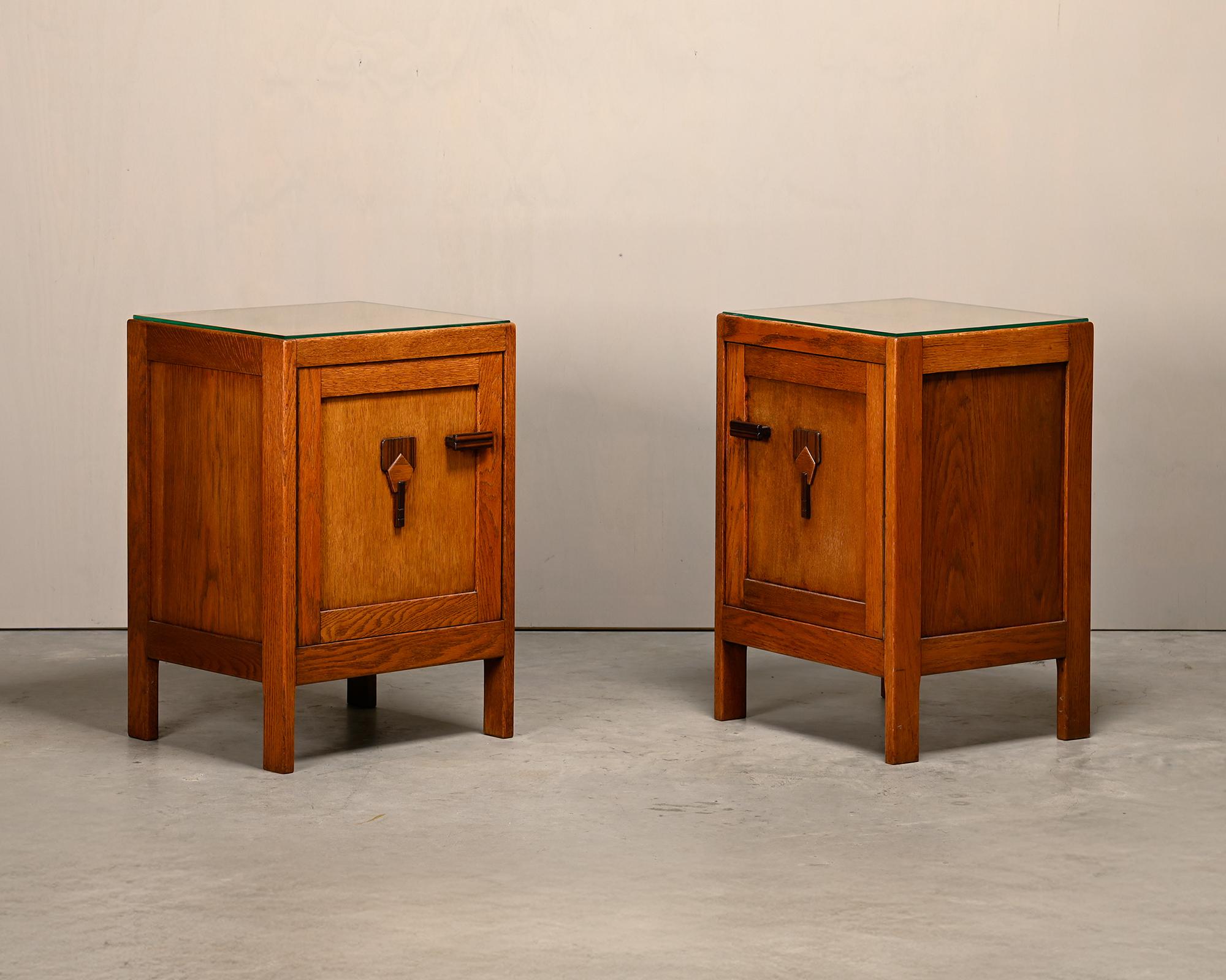 Coppia di comodini o comodini Art Déco nello stile della Scuola di Amsterdam, Paesi Bassi, anni Trenta. Basi in rovere massiccio con dettagli ebanizzati e piani in vetro. Il tutto in ottime condizioni originali con bellissime venature del legno
