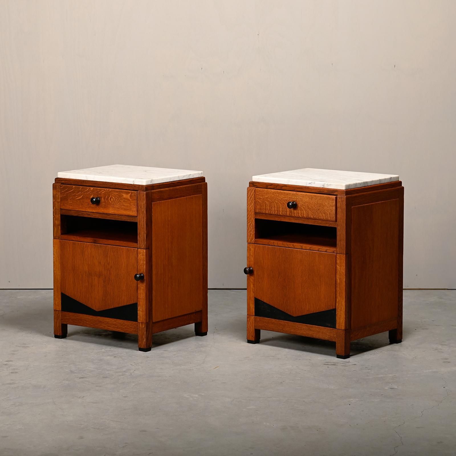 Stunning pair of Art Deco bedside tables or nightstands in the style of the Amsterdam School, Netherlands, 1930s. Solid oak bases with ebonized details and marble tops. All in very good original condition with beautifull aged wood grain. Wear