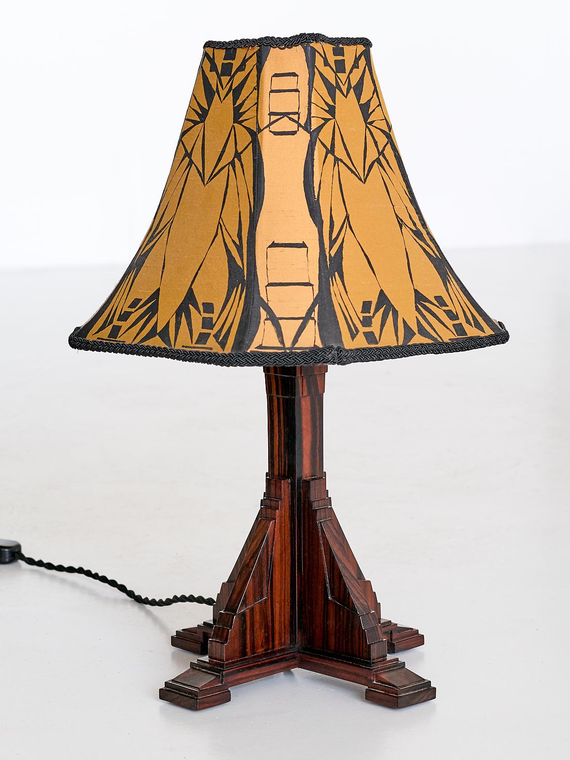 This elegant table lamp was produced in the Netherlands in the early 1930s. The tiered base rests on four square feet and is made of a veneered Macassar ebony with a striking wood grain. The meticulous manner in which the veneer has been applied