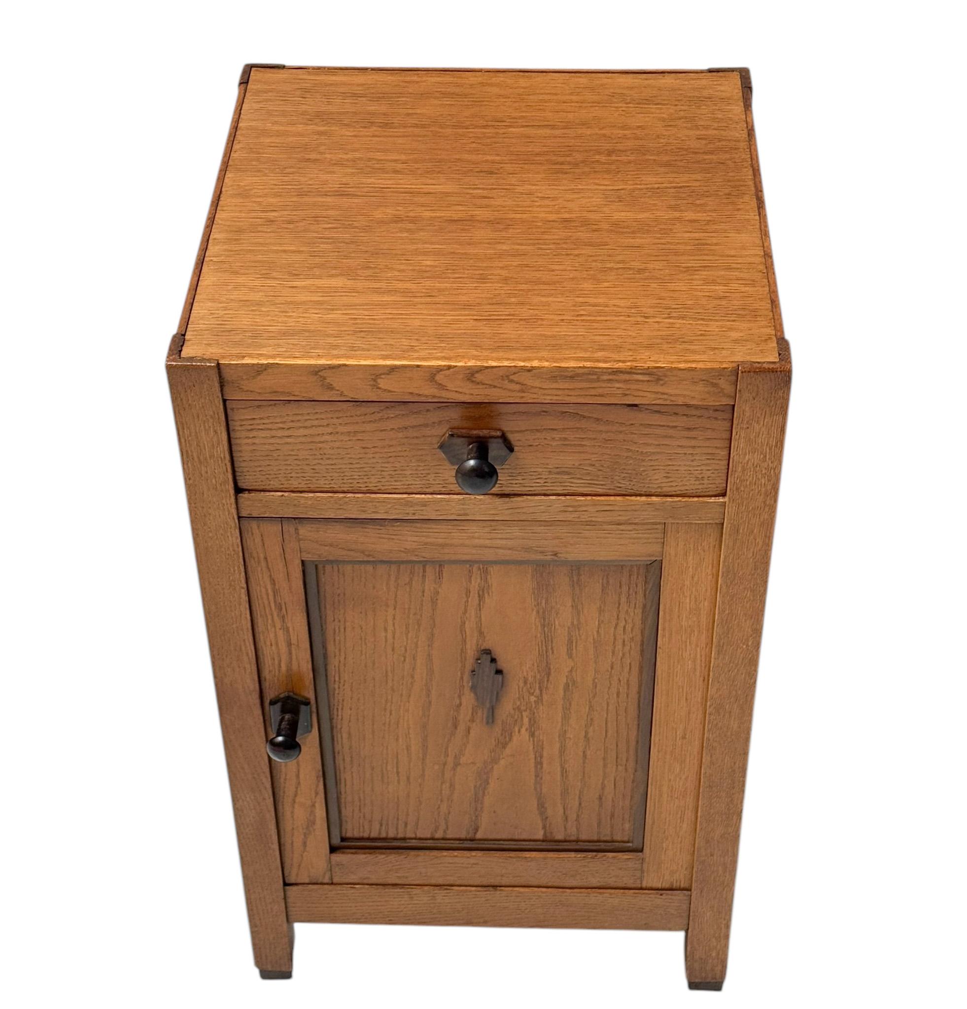 Stunning and elegant Art Deco Amsterdamse School nightstand or bedside table.Striking Dutch design from the 1920s.Solid oak base with original oak veneered top.Original solid macassar ebony knobs on door and drawer.This wonderful Art Deco