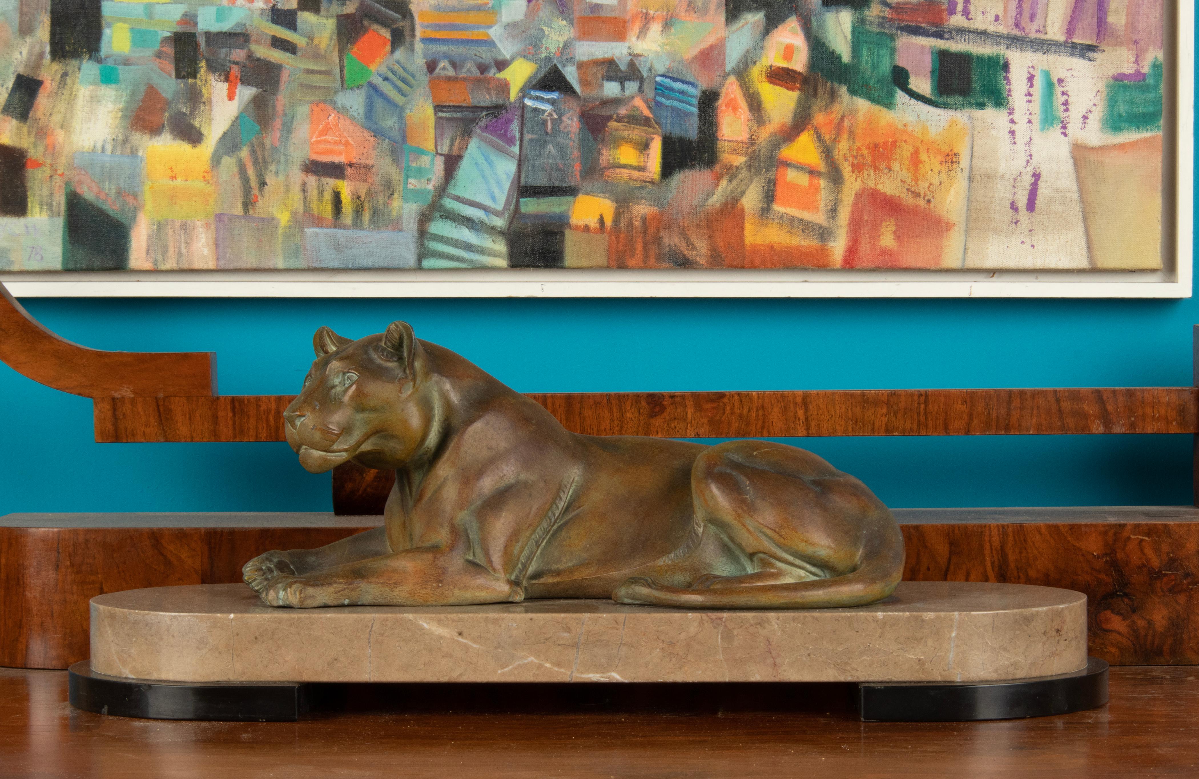 Decorative animal sculpture of a lioness. This sculpture is made of spelter, patinated in a green/brownish bronze colour. The base is made of marble. The sculpture dates from the Art Deco period, circa 1930. 
It is not signed, maker unknown. Some