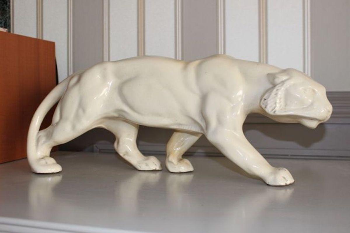 Cream-ivory crackled ceramic, representing a panther. Art Deco period and style. 1920-1940
In very well-preserved condition. The varnish is superb and the shade has remained very homogeneous.
The vent hole (pictured with the index finger) is a