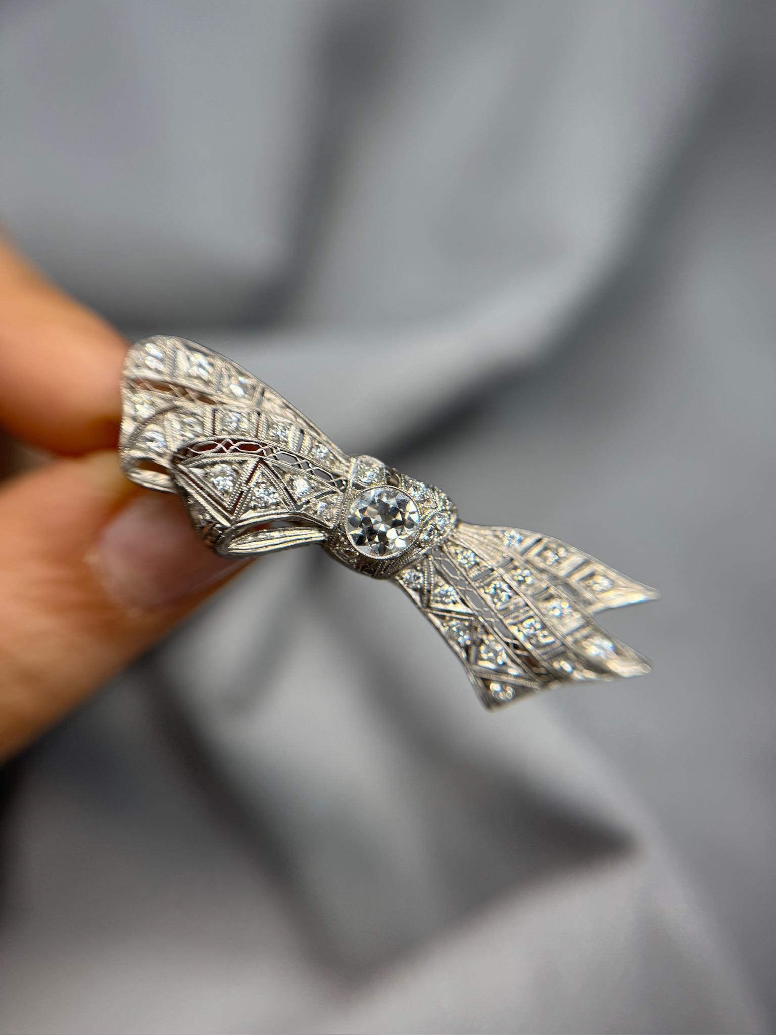 Elegante y refinado, este broche de lazo antiguo Art Decó presenta un impresionante diamante de talla europea antigua de 0,90 ct en el centro, rodeado de 35 piedras de realce que suman un total de 2,00 ct. Elaborada en lujoso platino y con un peso