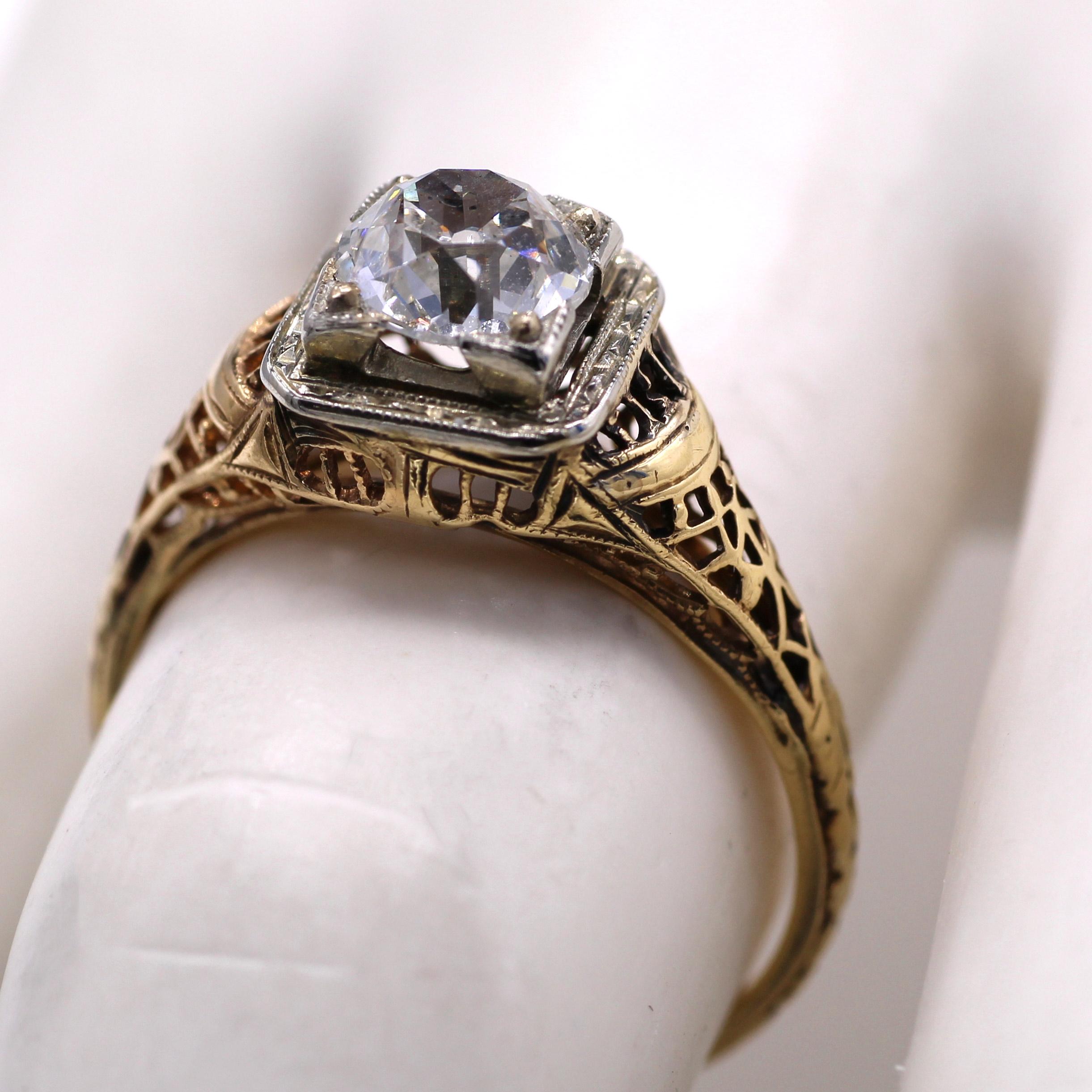 This charming engagement ring from ca 1930 has beautiful detailed ajour work all around the gallery and the shanks of the ring. Centrally set and slightly raised sits a bright and lively Antique Cushion brilliant weighing 1.04 carats. The diamond is