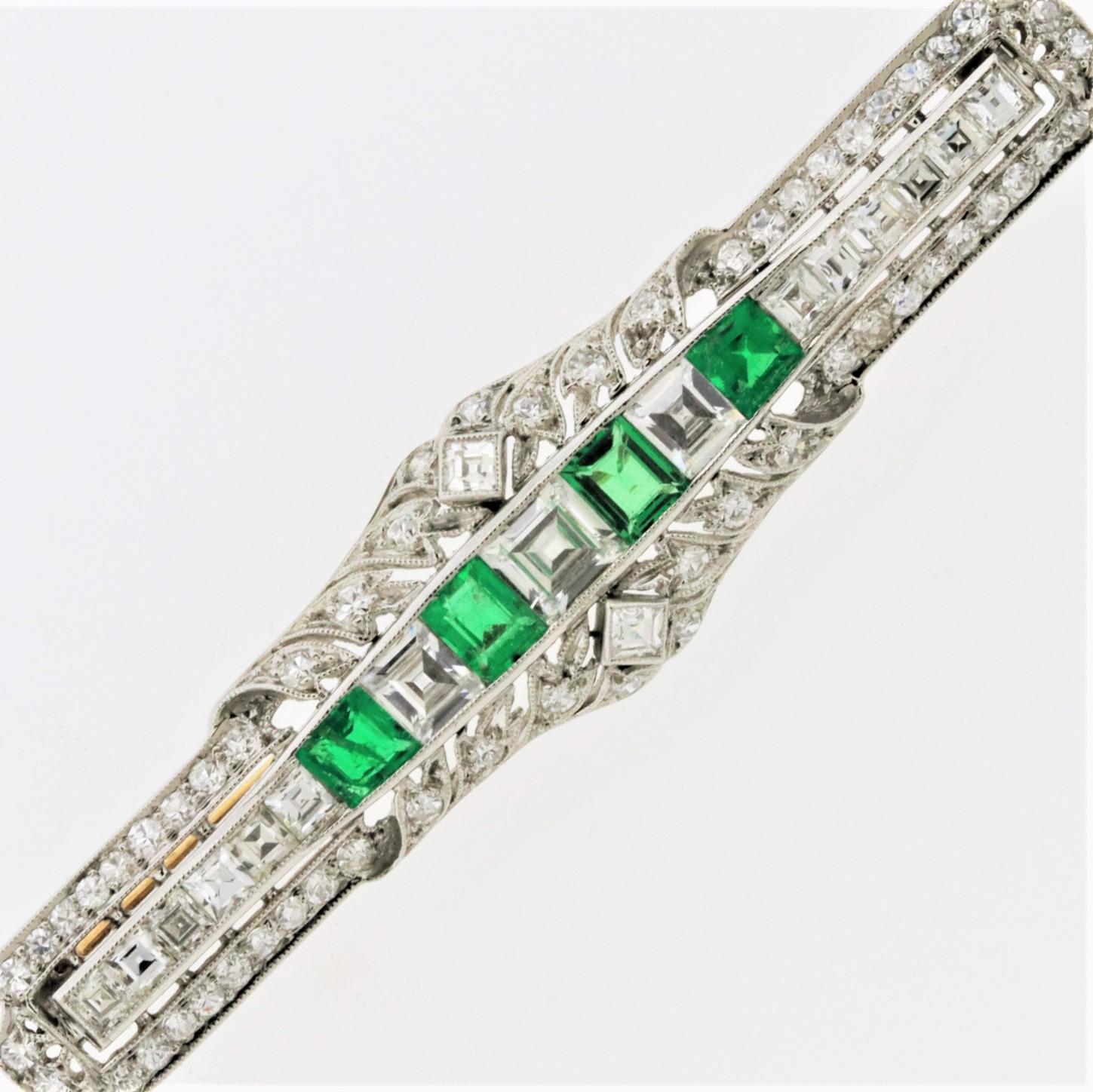A top-quality brooch with fine gem emerald and diamonds made in the early Art Deco movement, circa 1925. It is an early Art Deco piece as it has some elements of Edwardian era garland motifs on the outer top and bottom of the piece while the center