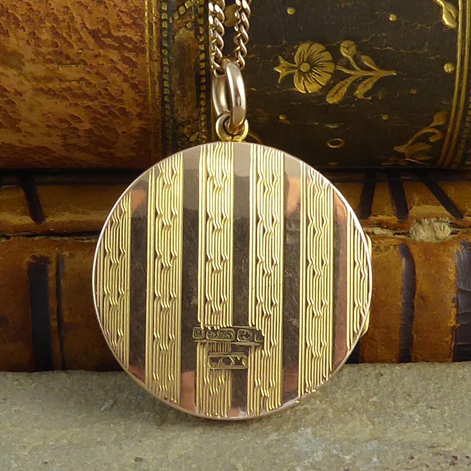 An Art Deco locket circa 1920's with engine-turned engraving typical of the era.  The locket is round and has been engraved on both sides with a striped pattern of plain polished stripes alternating with a reeded pattern stripe further adorned with