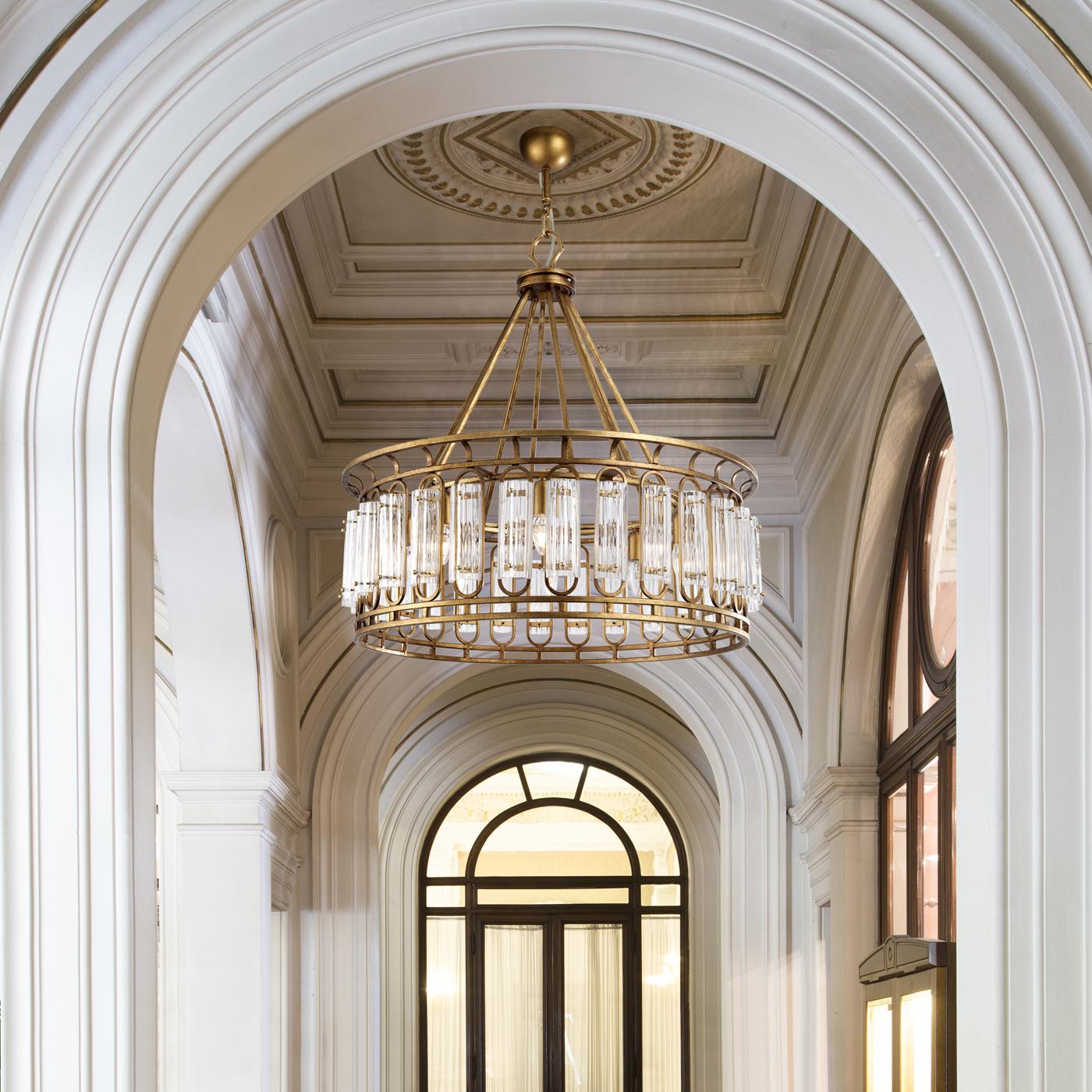 A bold homage to the dynamism of Art Deco art, this exceptional chandelier expertly combines traditional inspiration with contemporary taste. The imposing metal frame covered with antique gold leaf is attached to the ceiling by means of several