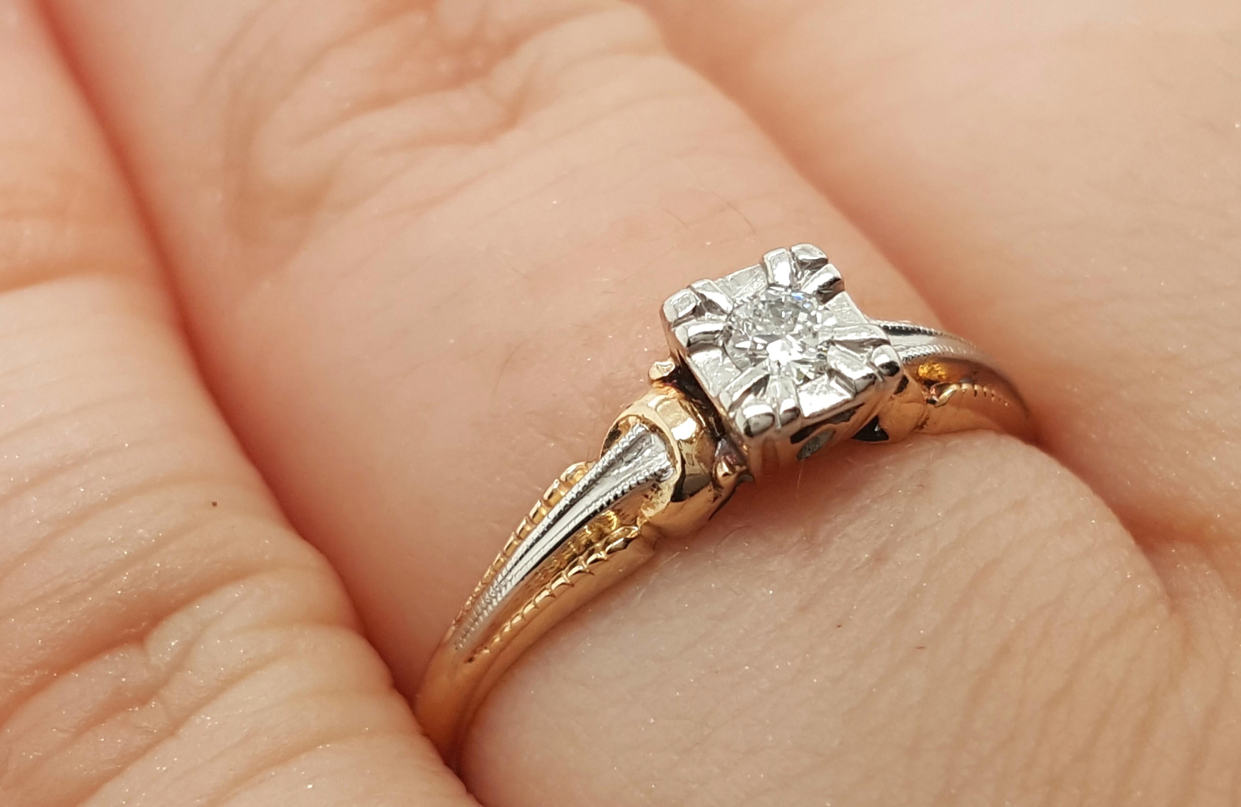 This cute Art Deco solitaire is a fine example of a filigree solitaire engagement ring crafted in 14 karat yellow and white gold. The antique Old European cut diamond is held in a hexagonal head, leading down to an intricate filigree design that