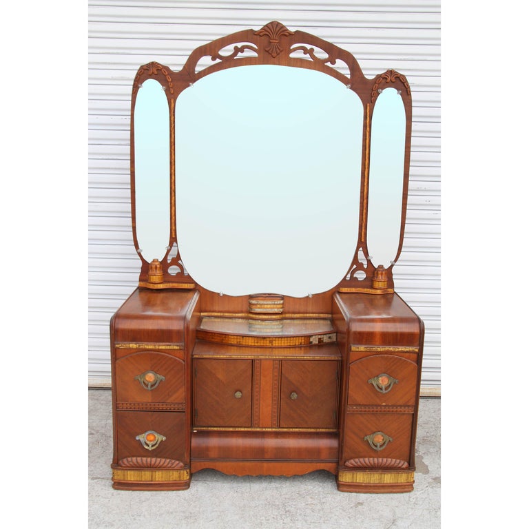 1920-1930s antique waterfall dresser 
 
Beautiful dresser, vanity with wood carvings on dresser, base, drawers, and mirror. 
Four deep drawers with Art Deco bakelite handles. Two door lower shelving.

